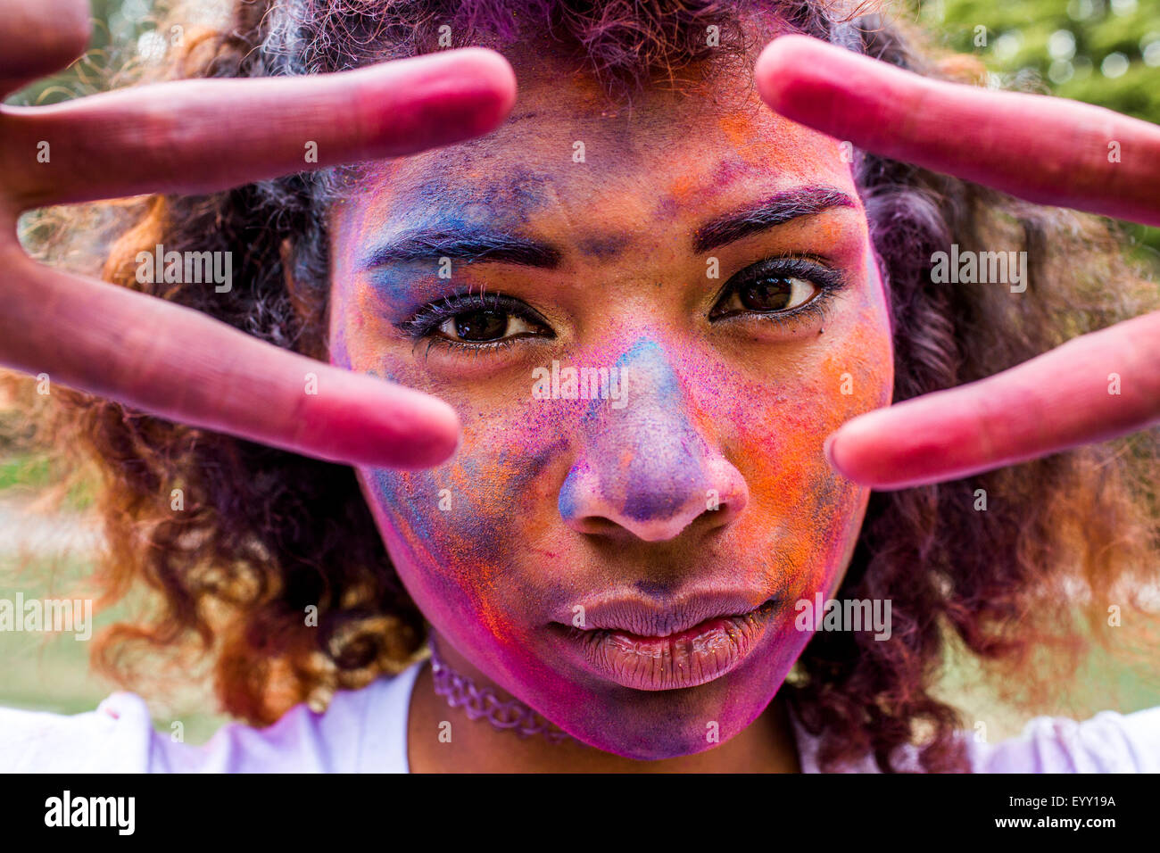 Mixed race woman covered in pigment powder gesturing peace signs Stock Photo