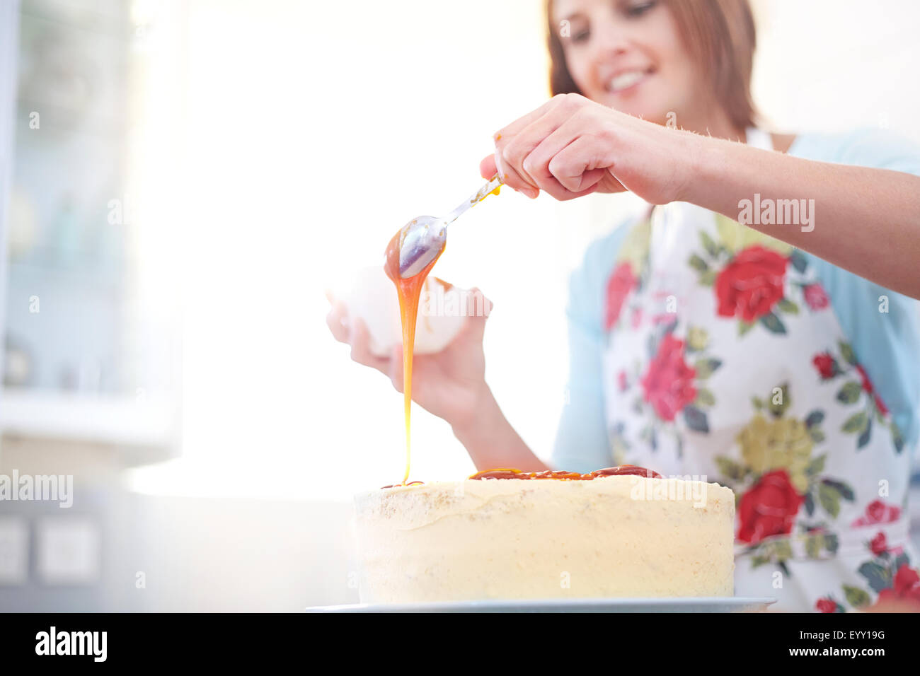 Woman pouring caramel over cake baking in kitchen Stock Photo