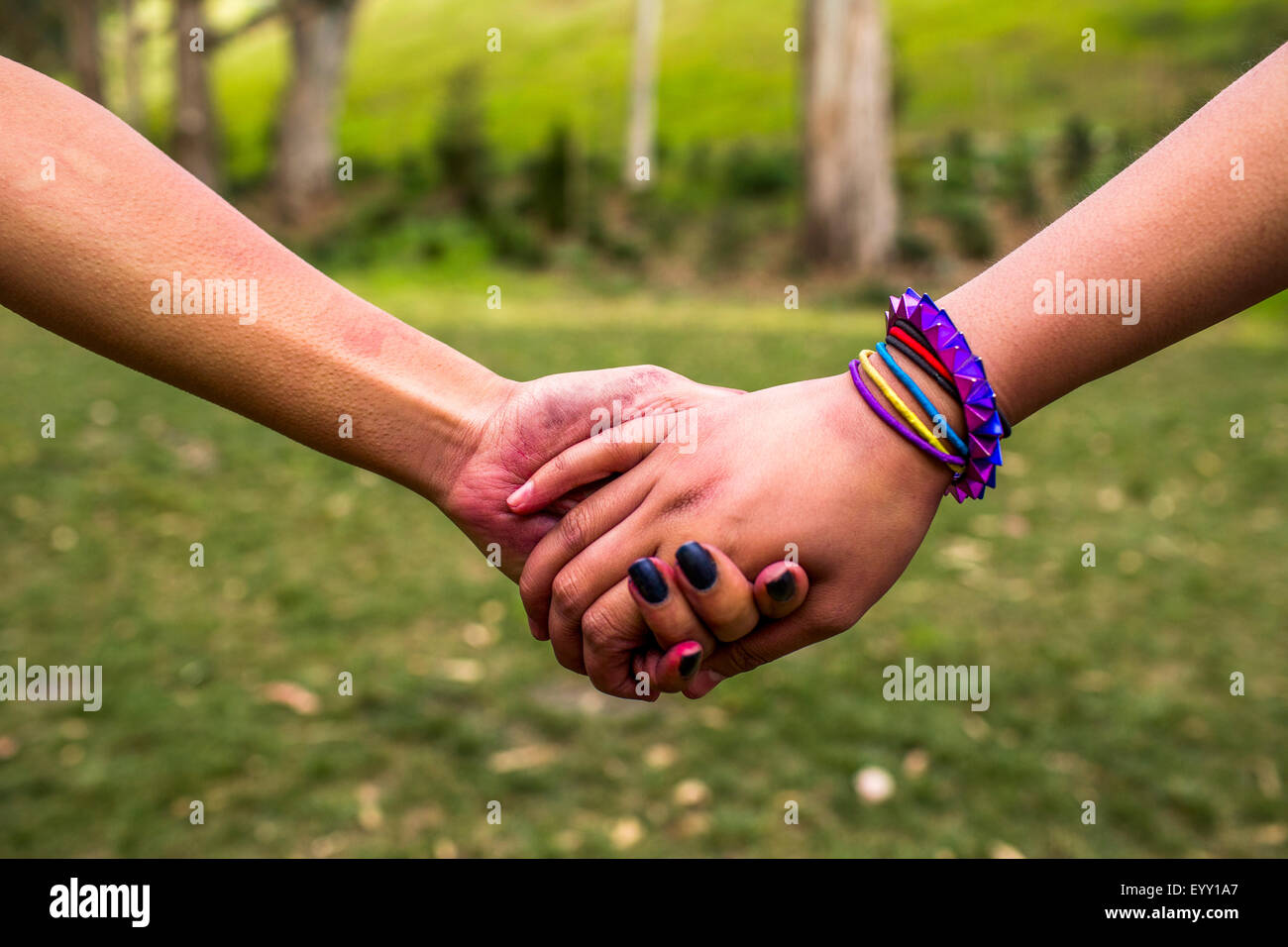 Close up of women holding hands in park Stock Photo