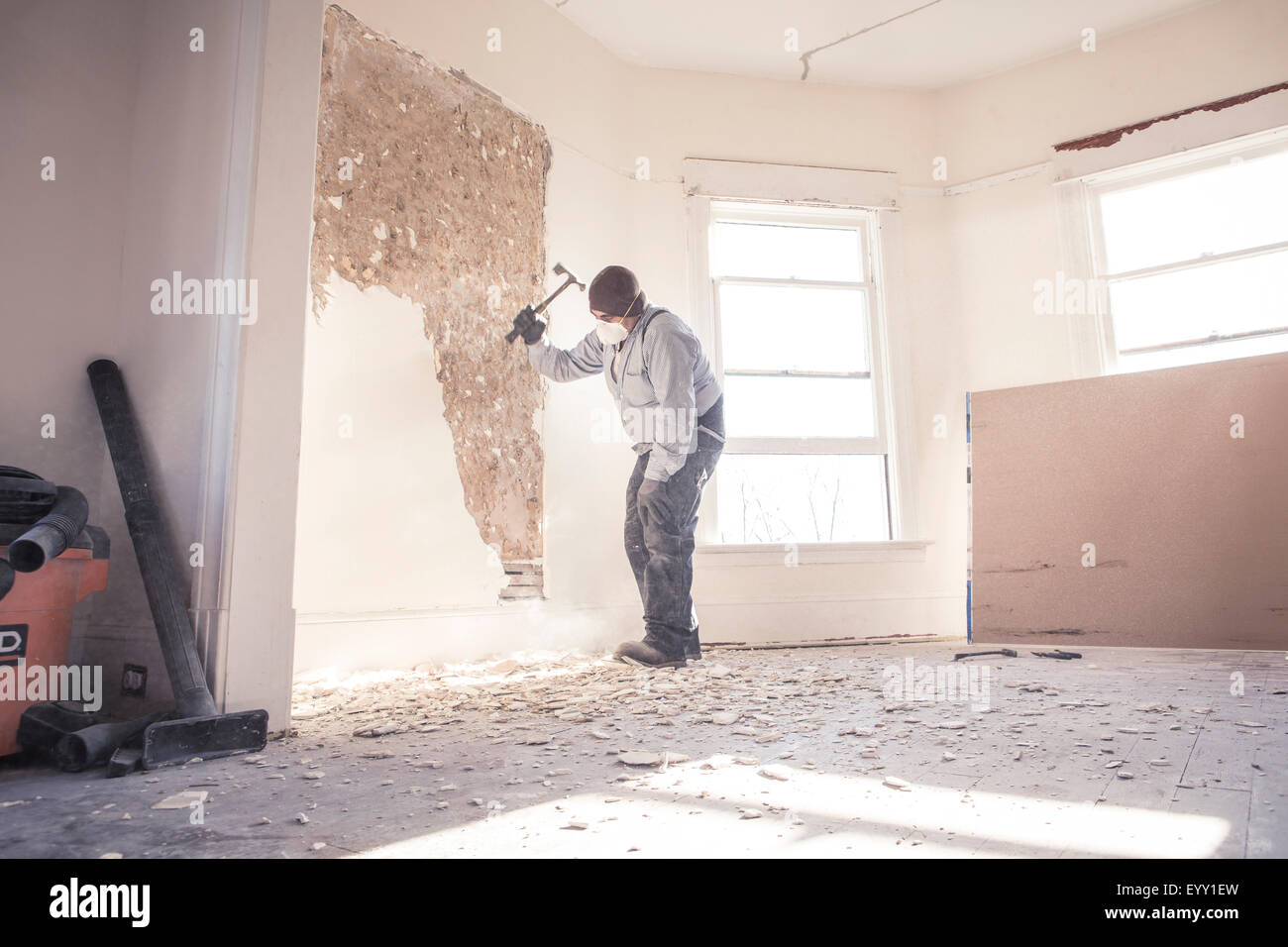Hispanic construction worker demolishing wall Stock Photo