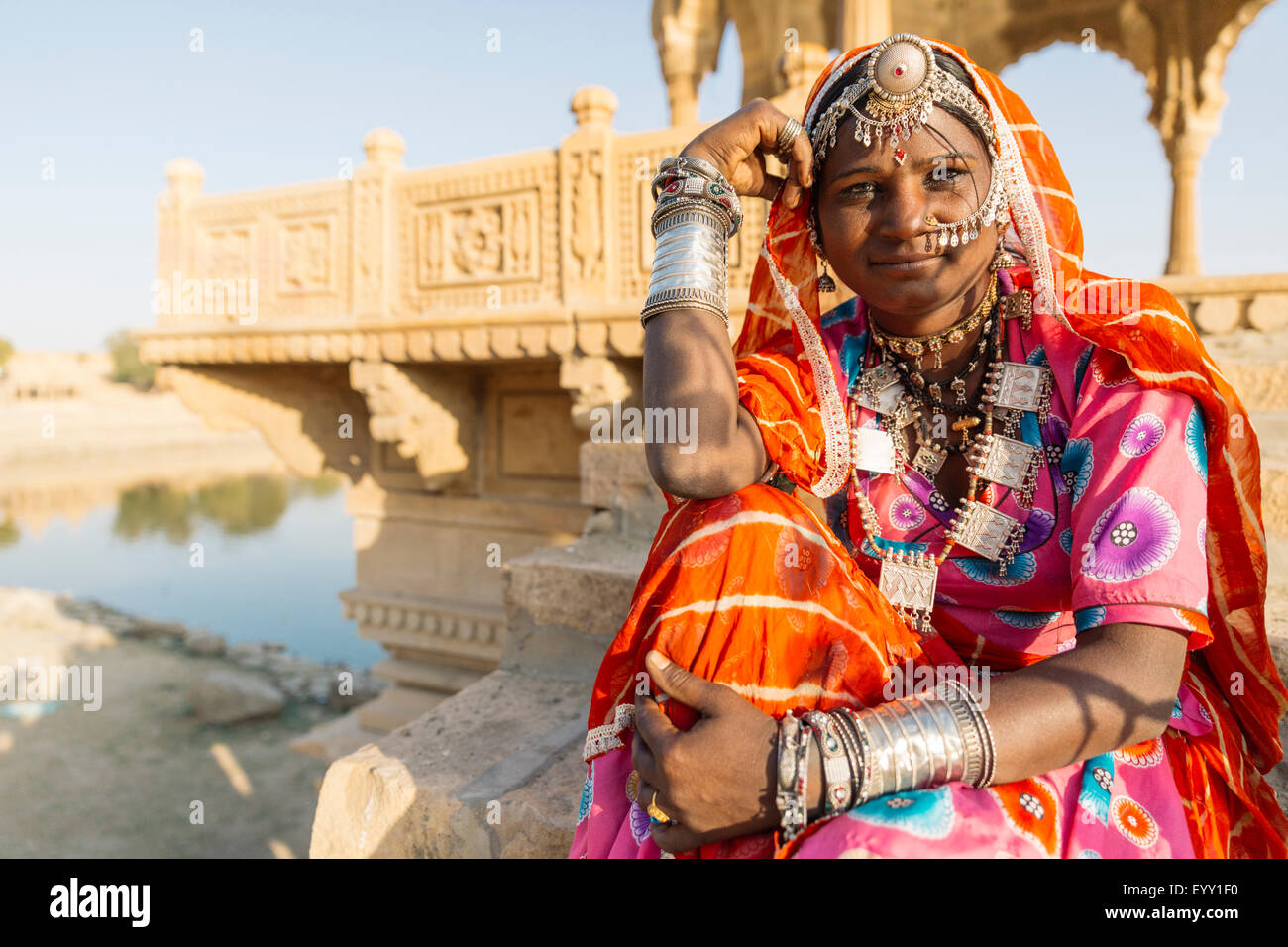 Indian woman wearing traditional jewelry sitting near monument, Jaisalmer, Rajasthan, India Stock Photo