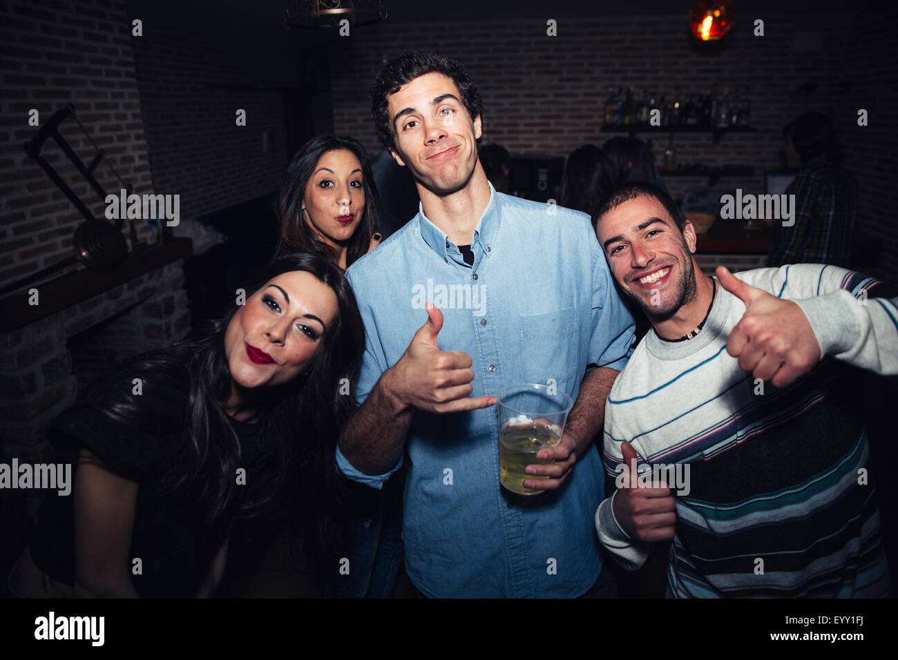 Laughing friends giving thumbs up in nightclub Stock Photo