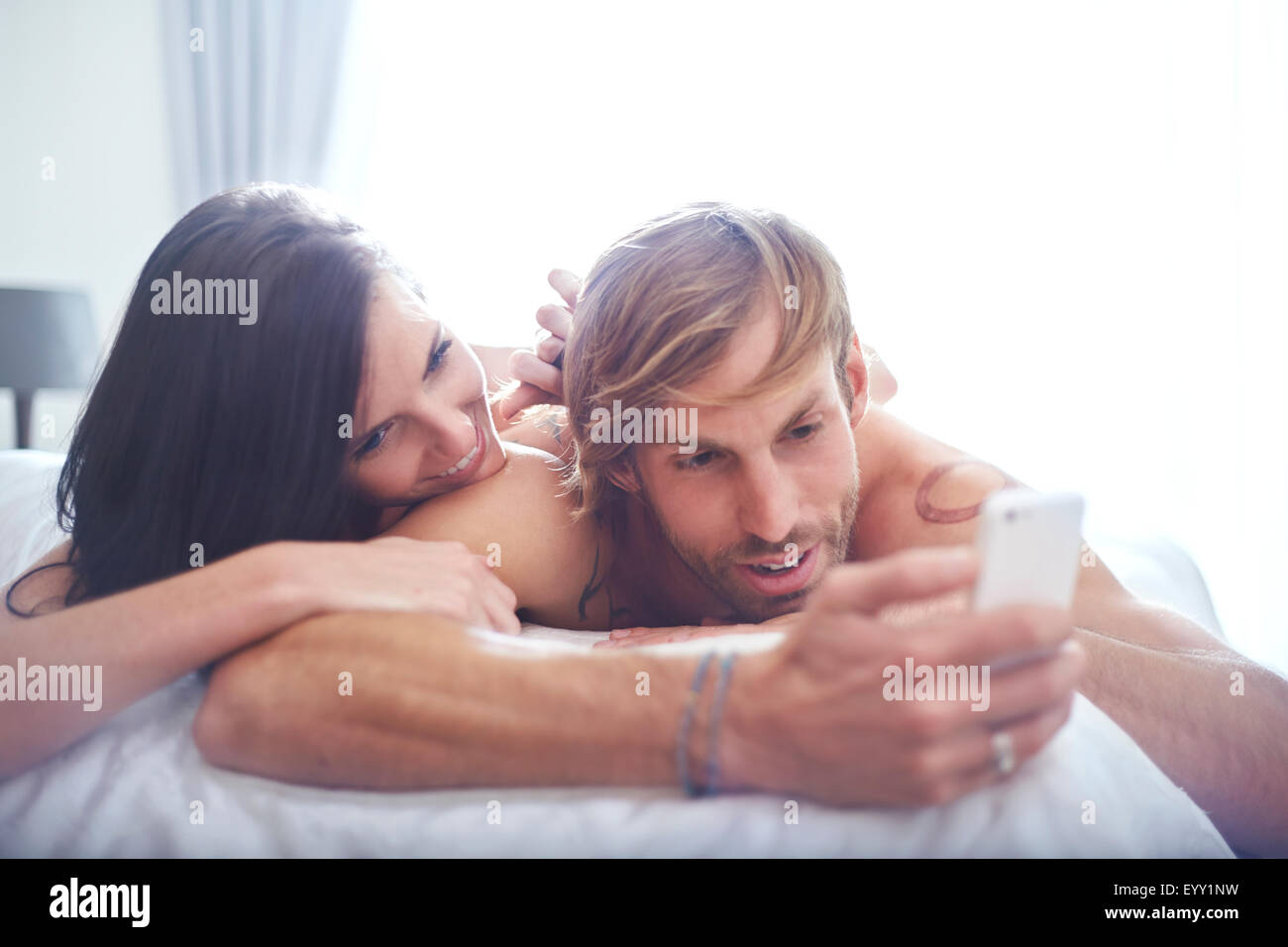 Couple relaxing on bed texting with cell phone Stock Photo