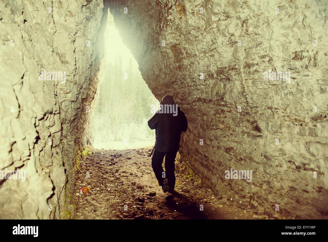 Caucasian hiker walking in rocky cave Stock Photo