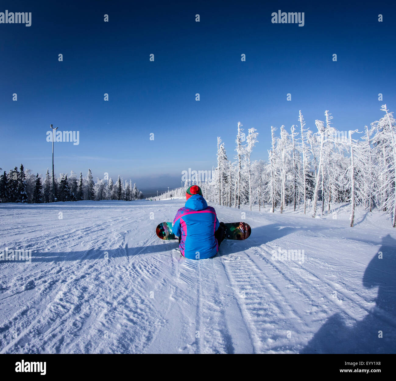 Caucasian snowboarder sitting on snowy slope Stock Photo