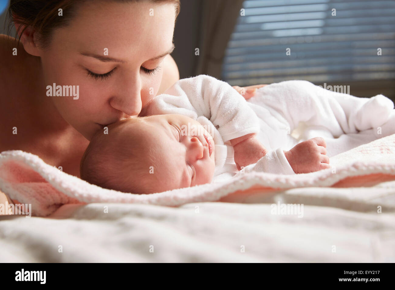 Mother kissing newborn baby on blanket Stock Photo