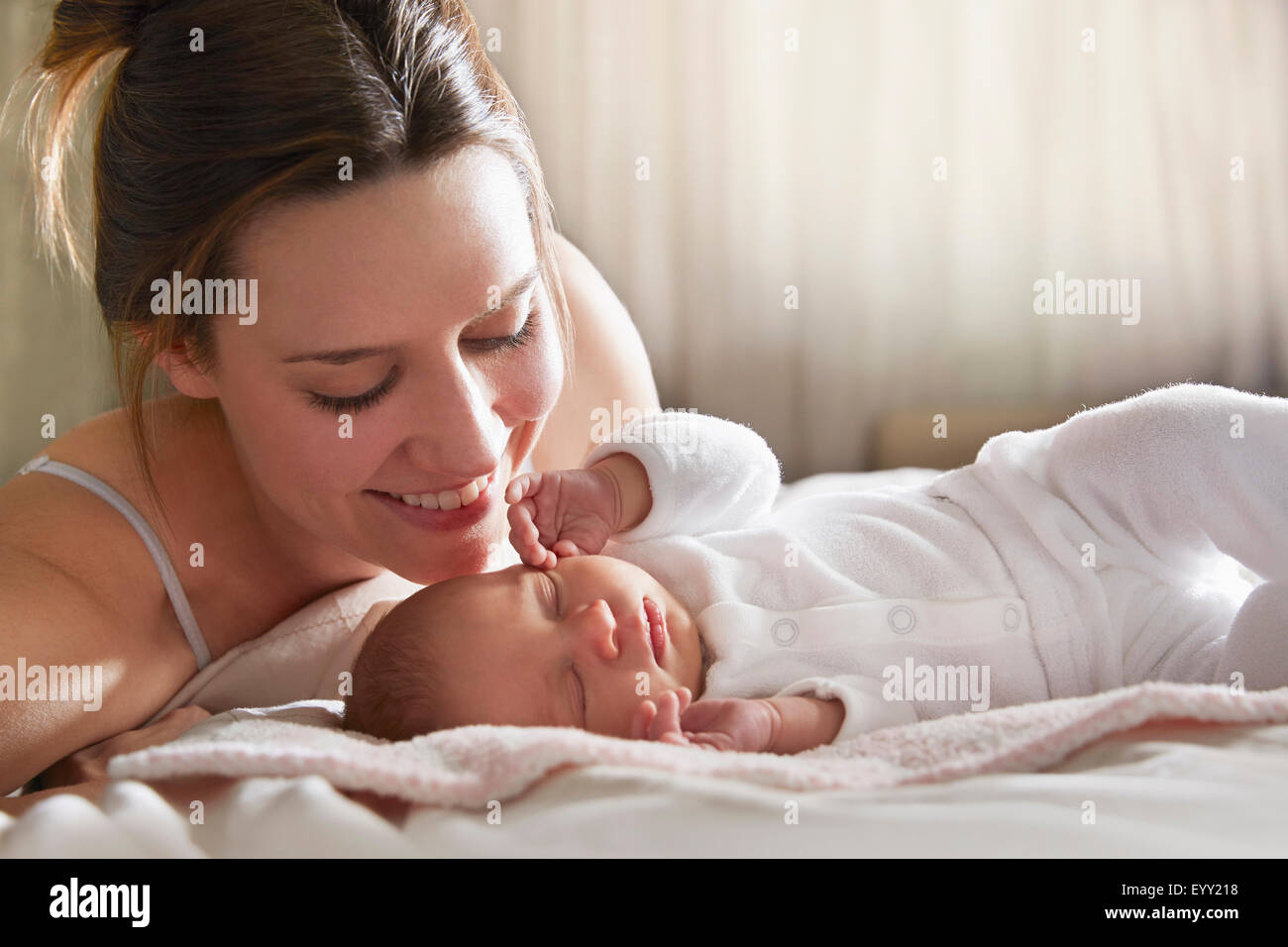 Mother admiring newborn baby on bed Stock Photo