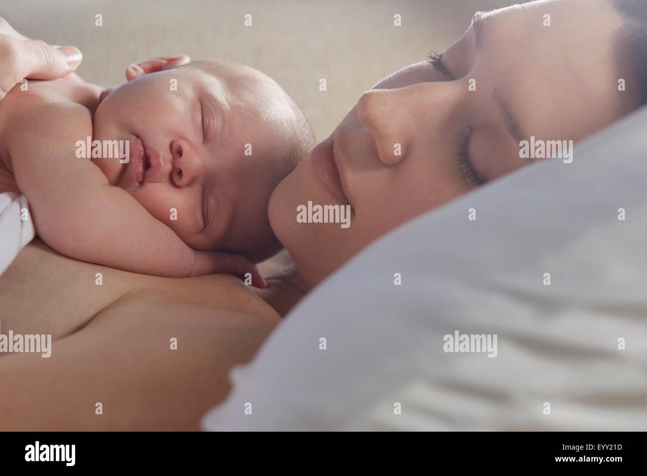 Mother sleeping with newborn baby on bed Stock Photo