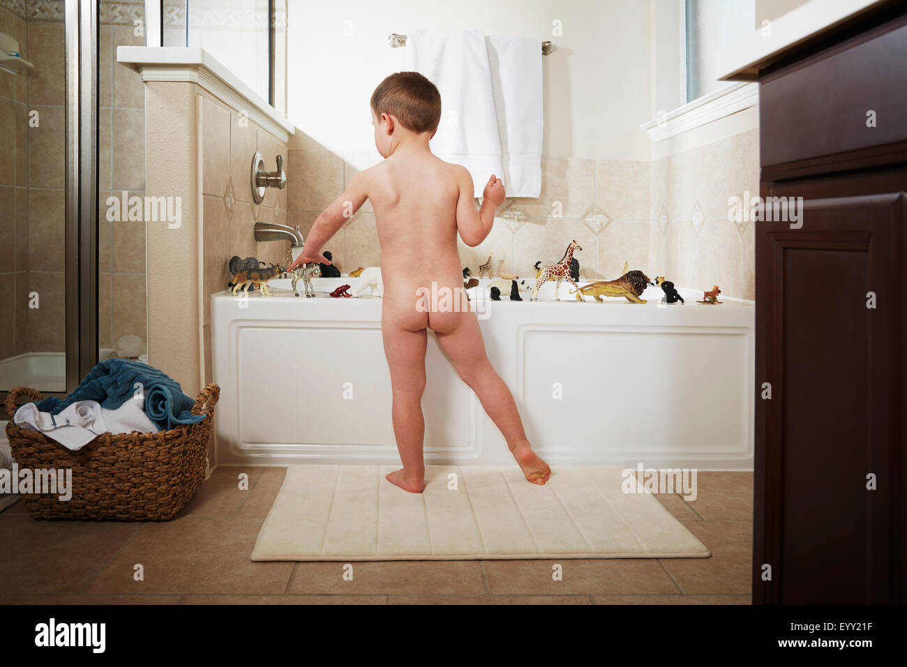 Nude Caucasian boy playing in bathtub Stock Photo