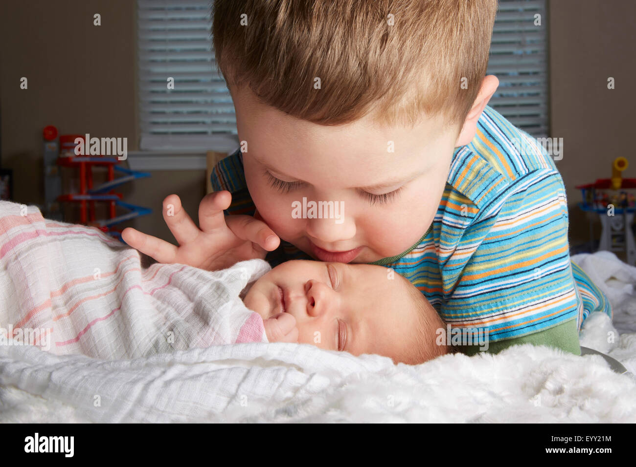 Boy admiring newborn sibling on bed Stock Photo