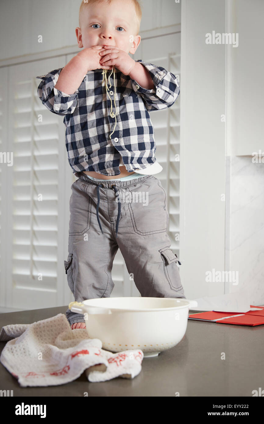 Caucasian boy standing on table playing with food Stock Photo