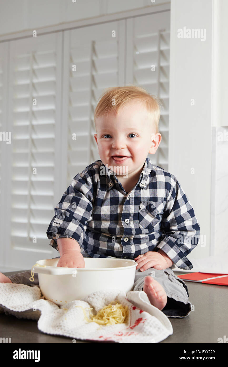 Caucasian boy playing with food in kitchen Stock Photo