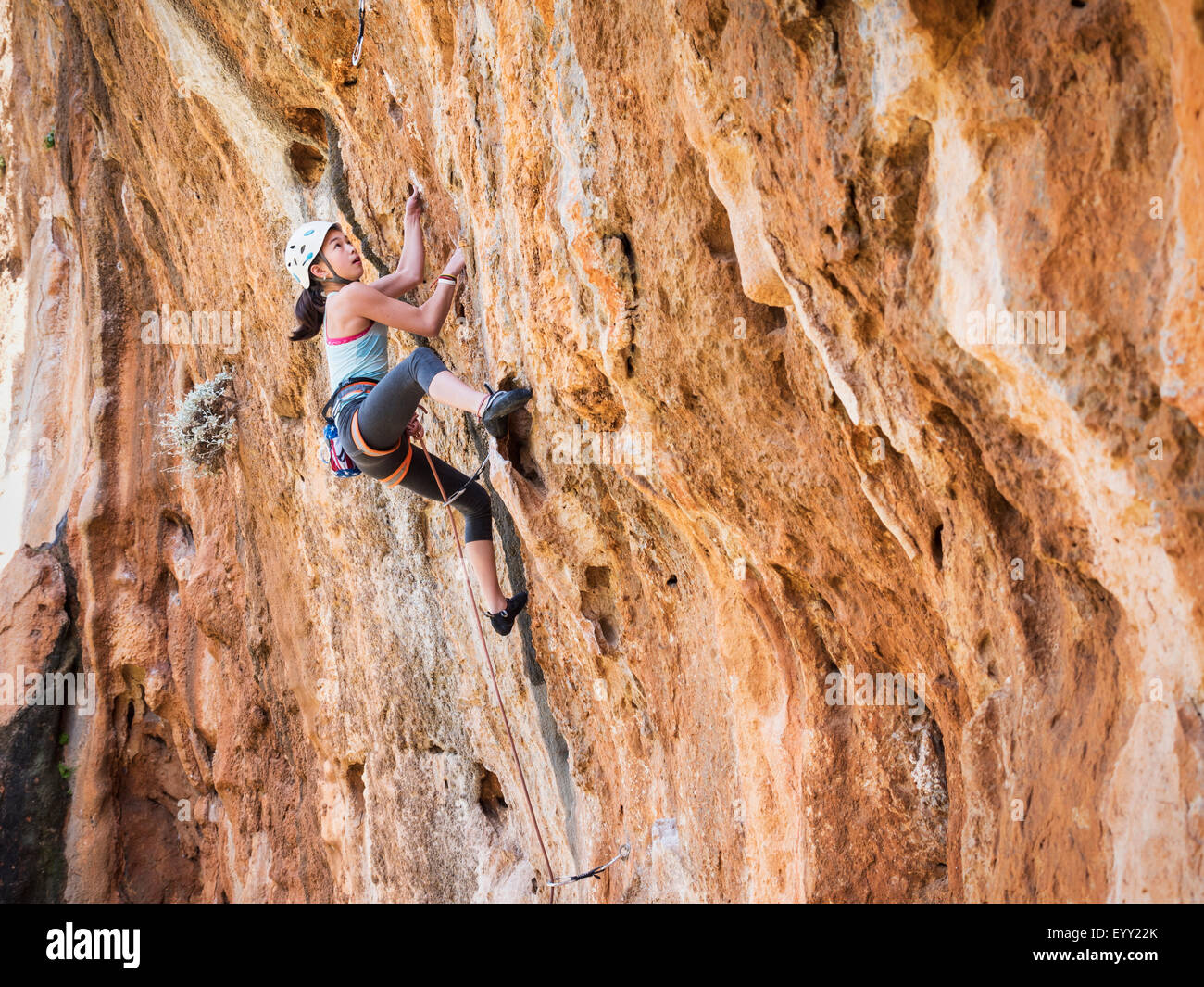 Mixed race girl climbing rock wall Stock Photo