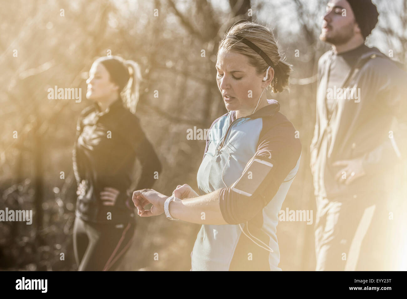 Caucasian runner checking fitness watch in forest Stock Photo