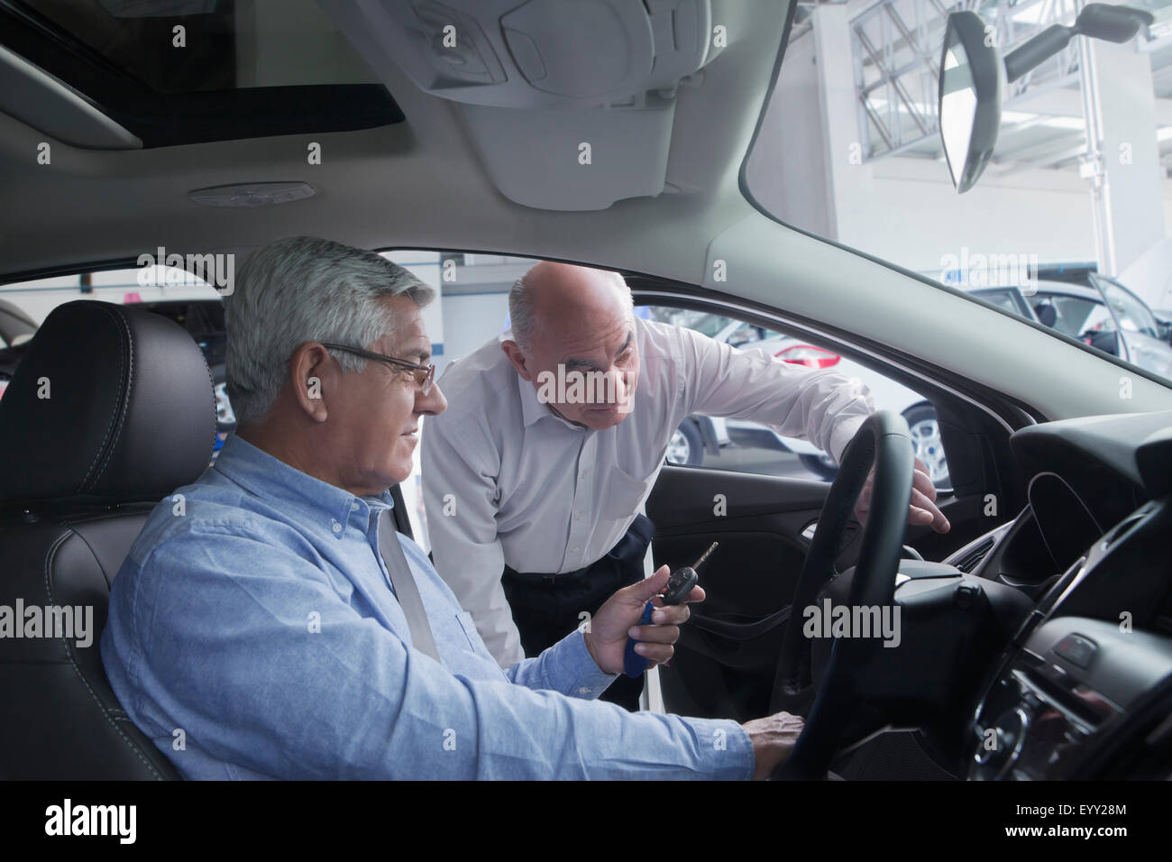 Hispanic car salesman showing customer new car Stock Photo