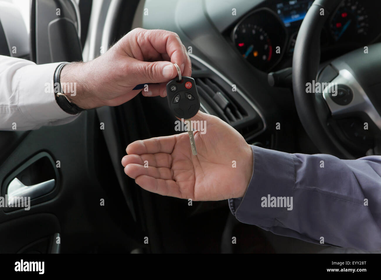 Hispanic car salesman handing keys to customer Stock Photo