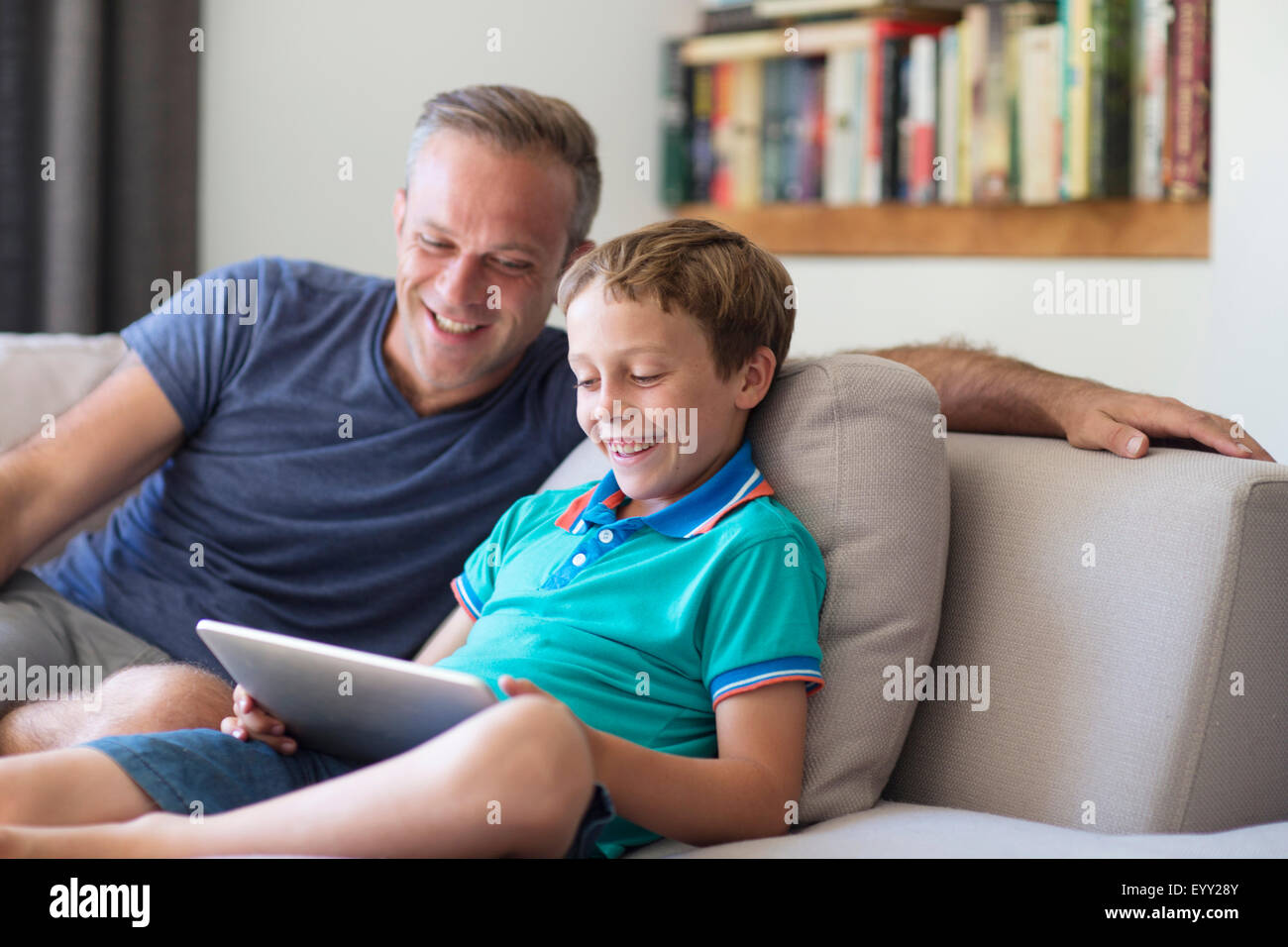 Caucasian father and son using digital tablet on sofa Stock Photo