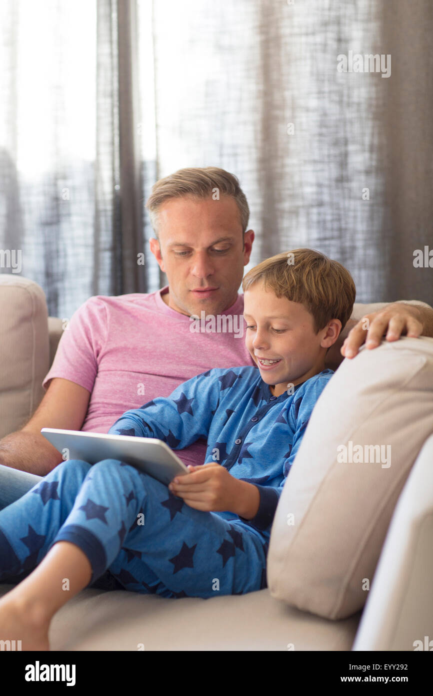 Caucasian father and son using digital tablet on sofa Stock Photo