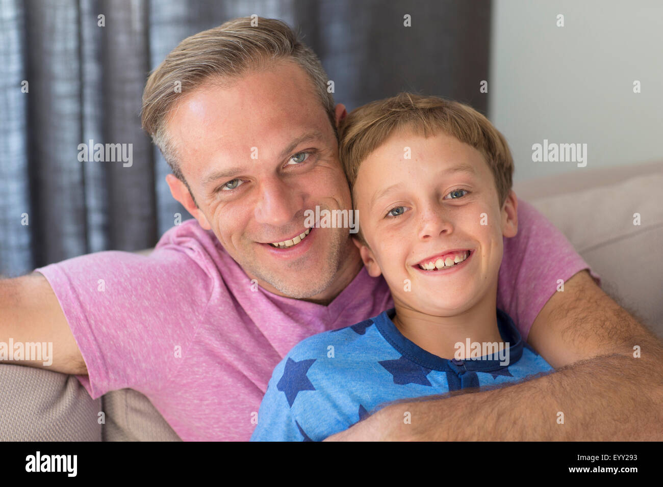 Caucasian father and son hugging on sofa Stock Photo