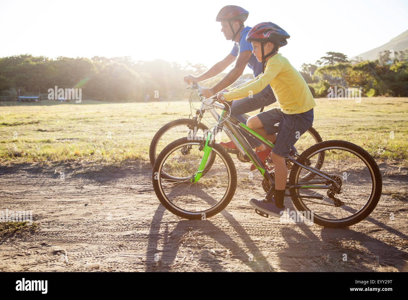 Caucasian father and son riding bicycles on dirt path Stock Photo