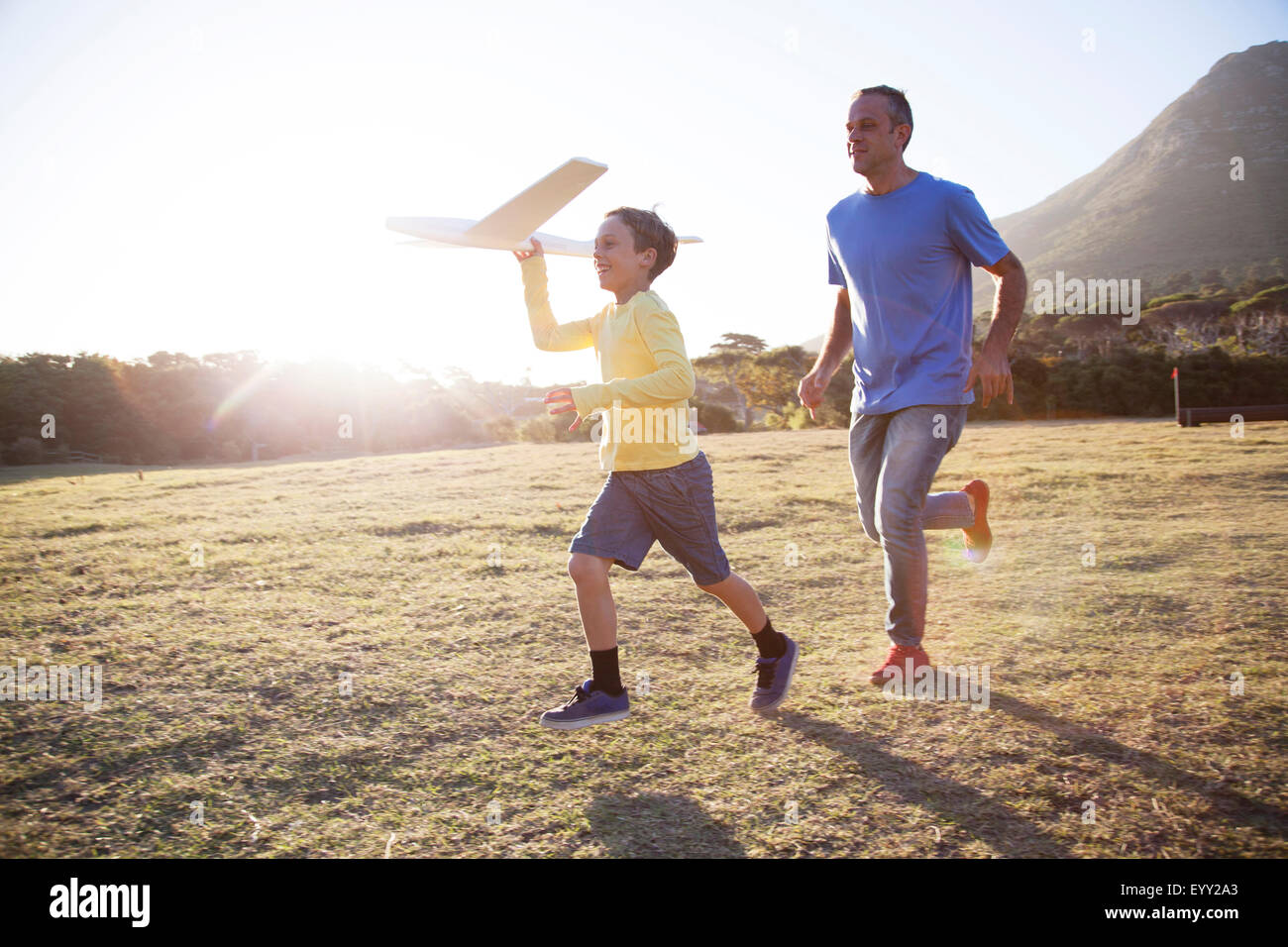 Caucasian father and son flying model airplane in field Stock Photo
