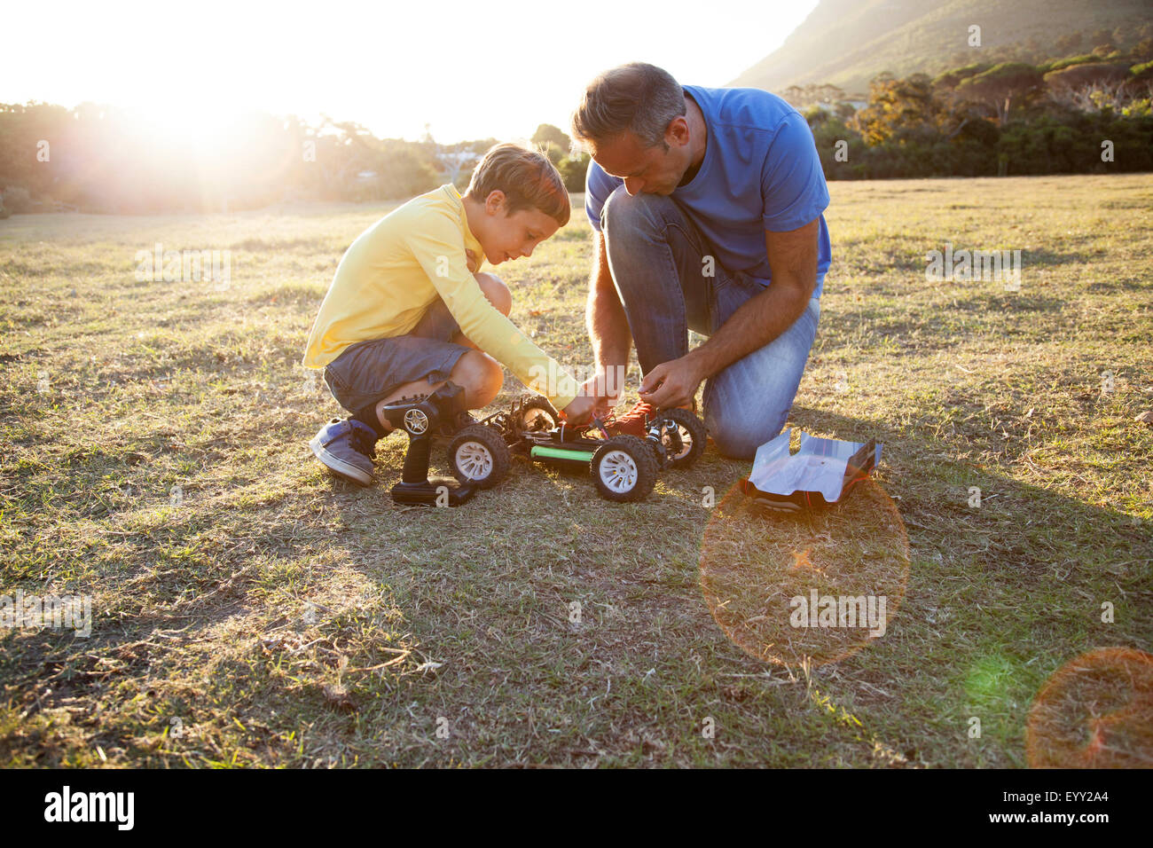 Caucasian father and son playing with remote control cars in field Stock Photo