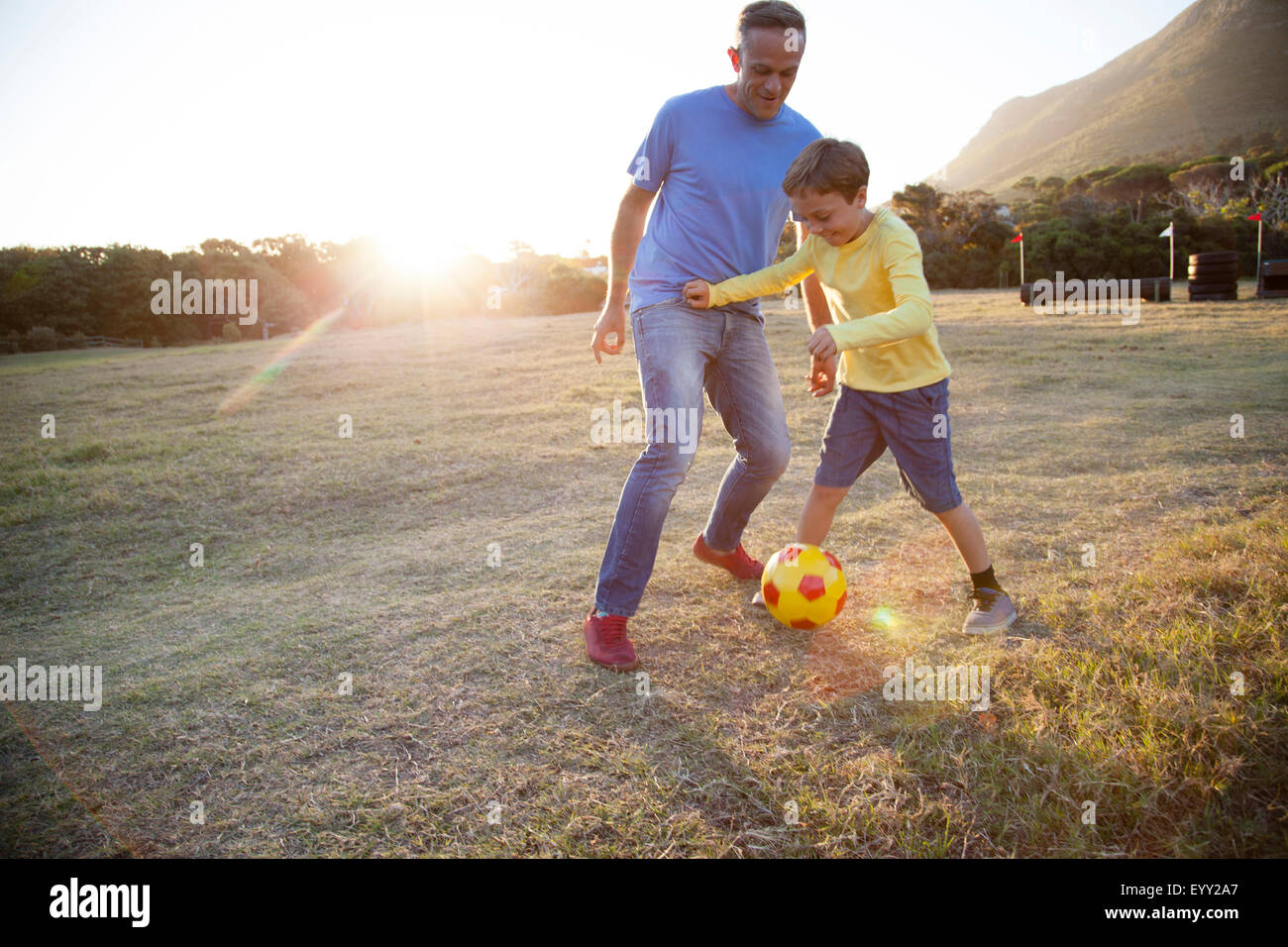 Caucasian father and son playing soccer in field Stock Photo