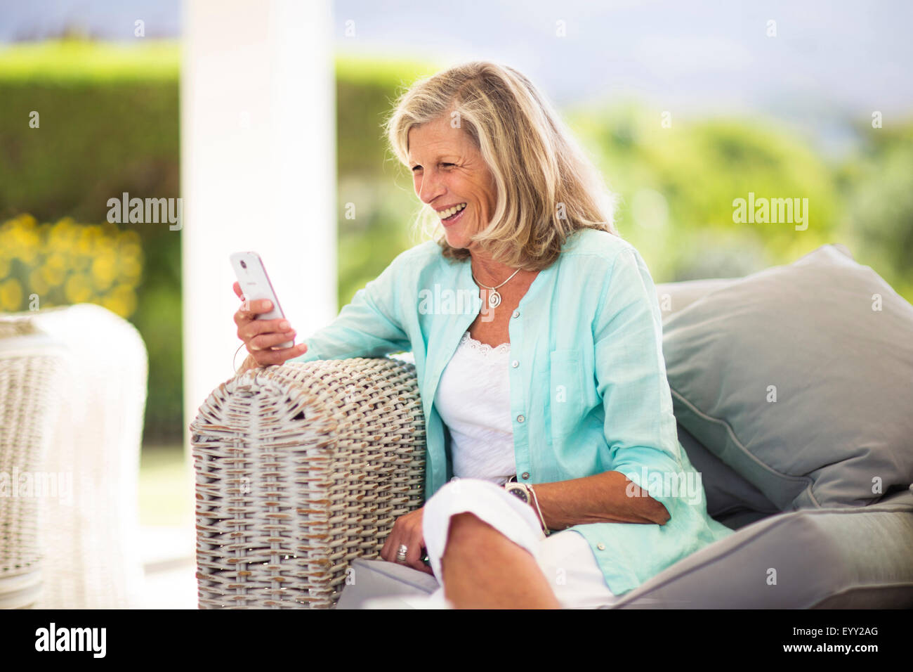 Caucasian woman using cell phone on sofa outdoors Stock Photo