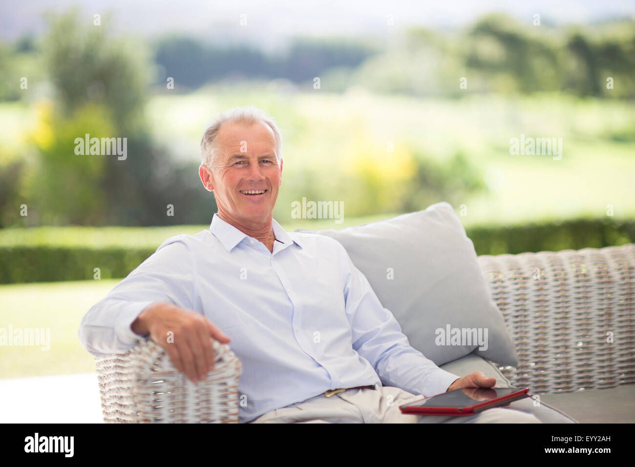 Caucasian man using digital tablet on sofa outdoors Stock Photo