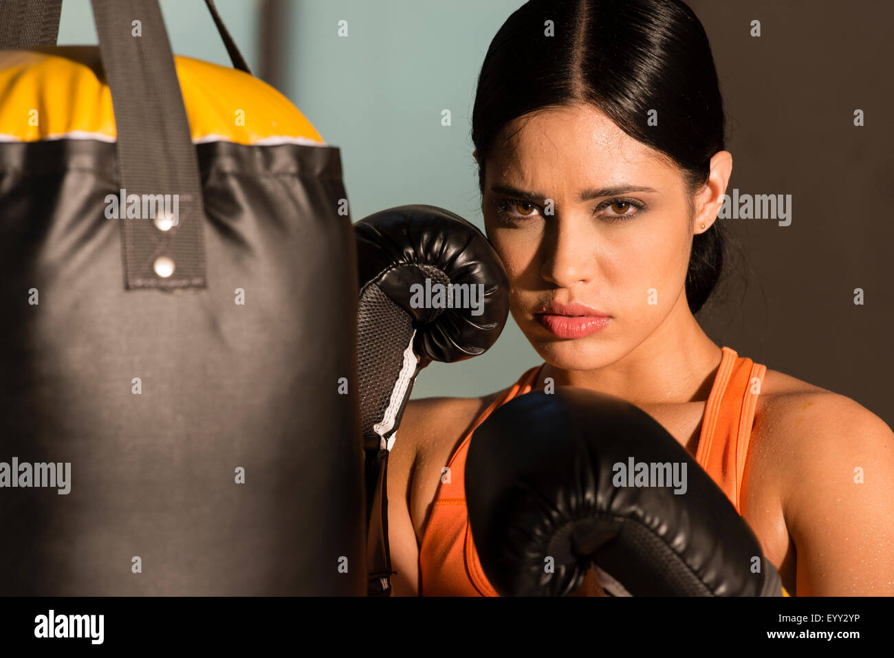 Hispanic boxer standing near punching bag in gymnasium Stock Photo