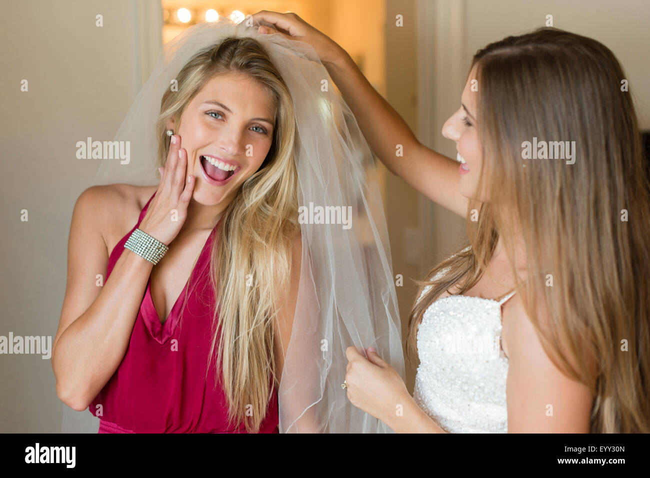 Caucasian bridesmaid wearing veil of bride Stock Photo