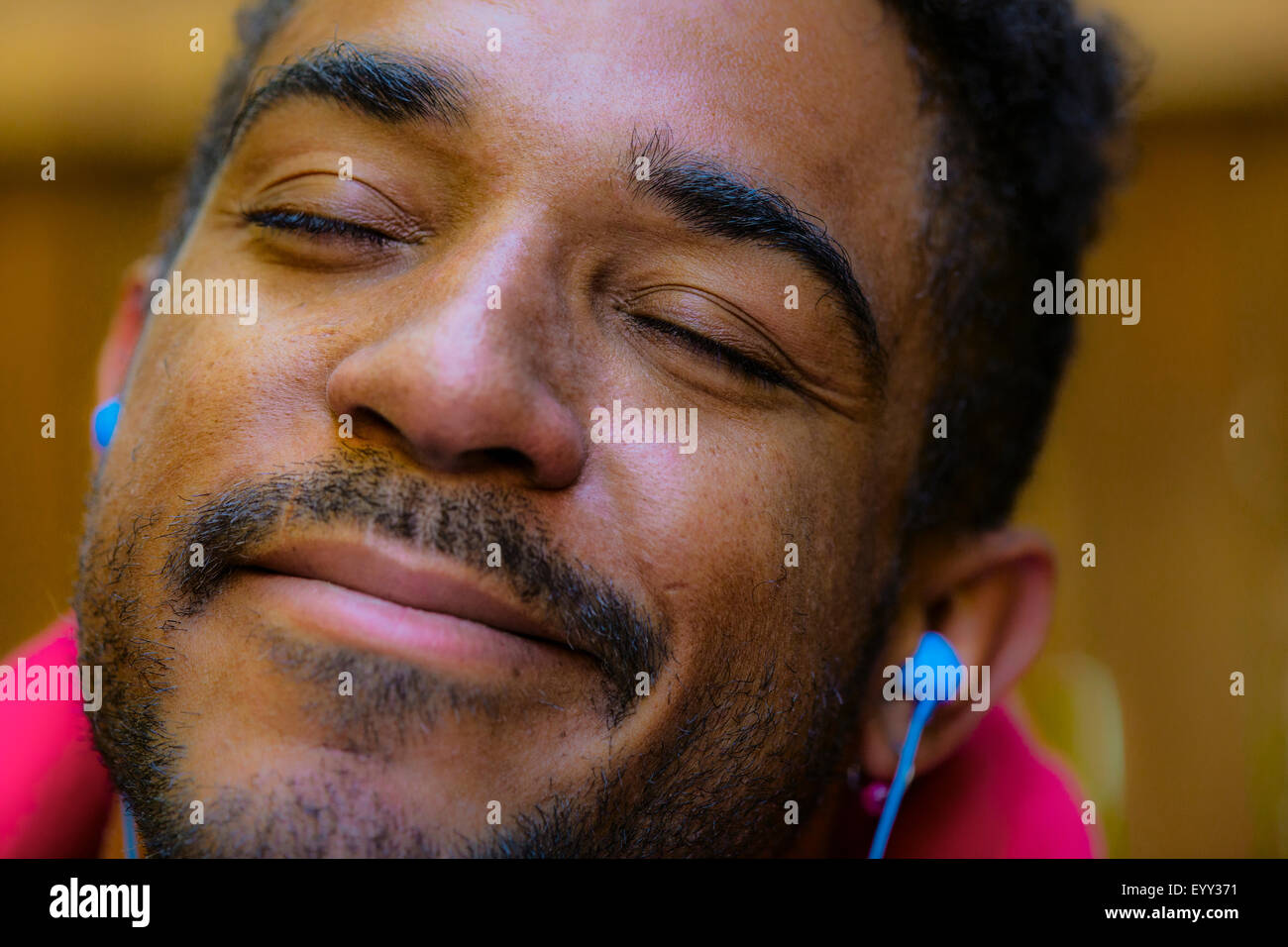 Close up of calm mixed race man listening to earbud Stock Photo