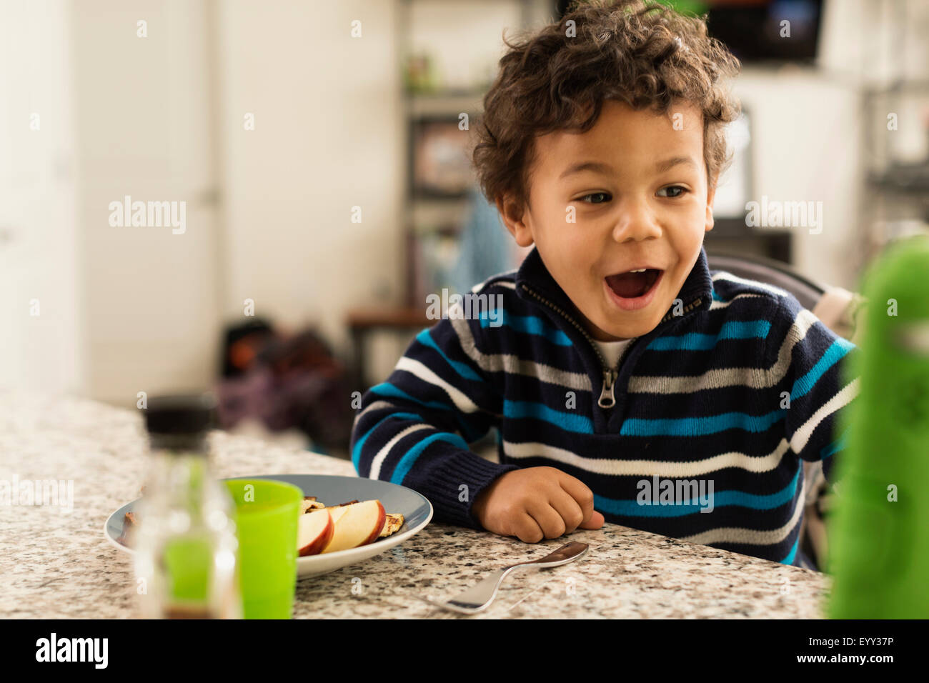 Mixed race boy eating at kitchen counter Stock Photo - Alamy