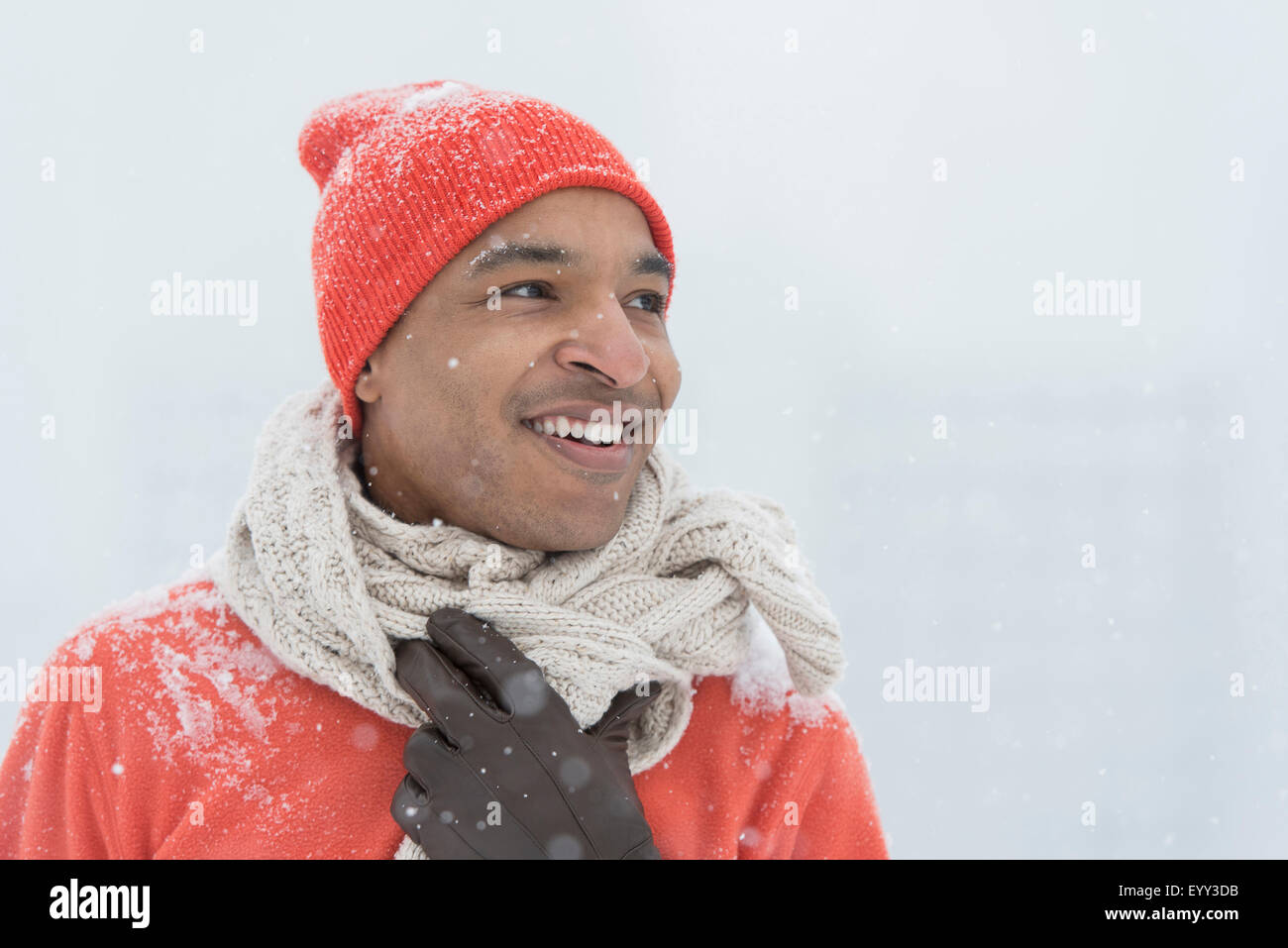 Black man wearing gloves and scarf in snow Stock Photo