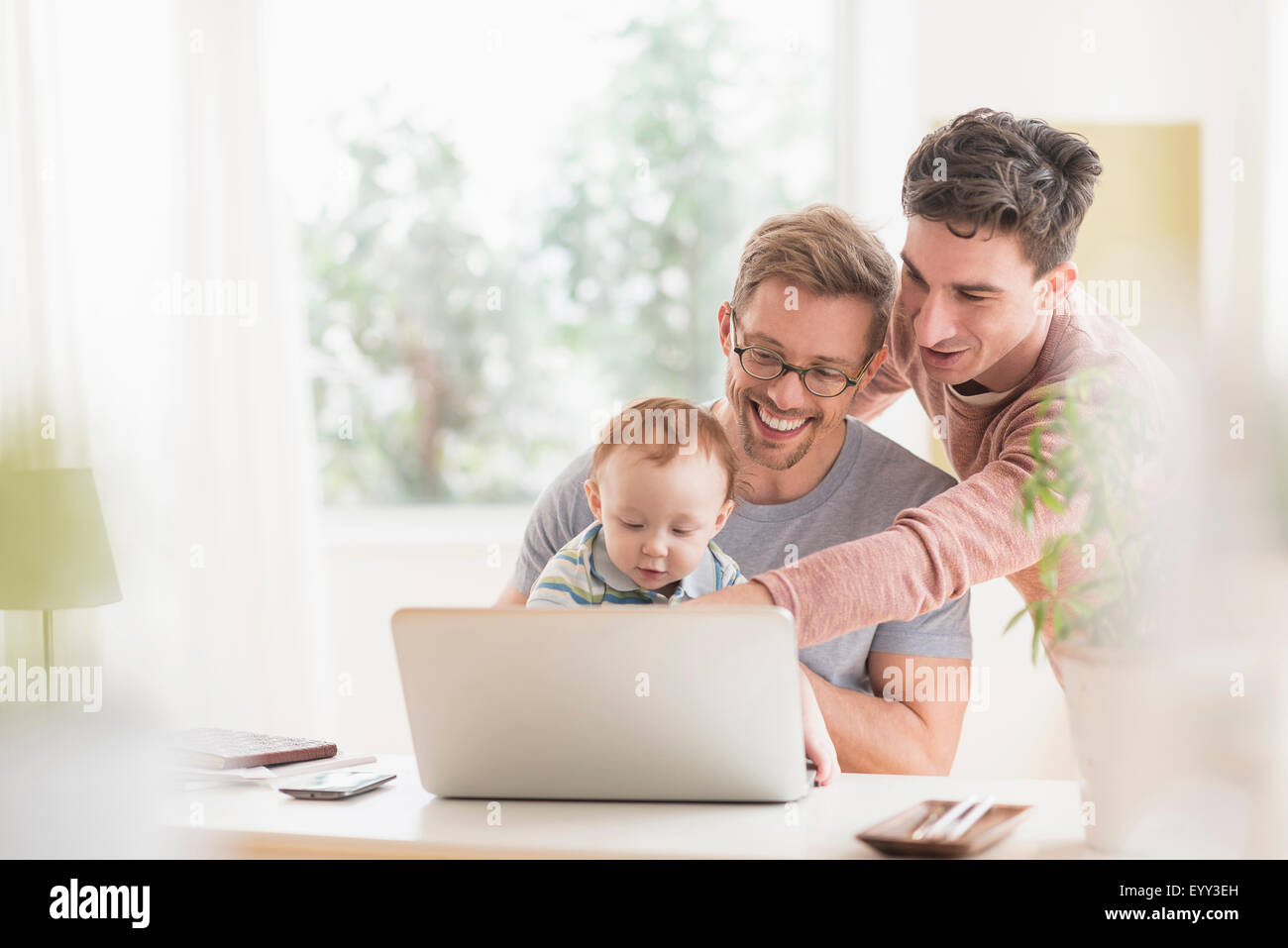 Caucasian gay fathers and baby using laptop Stock Photo