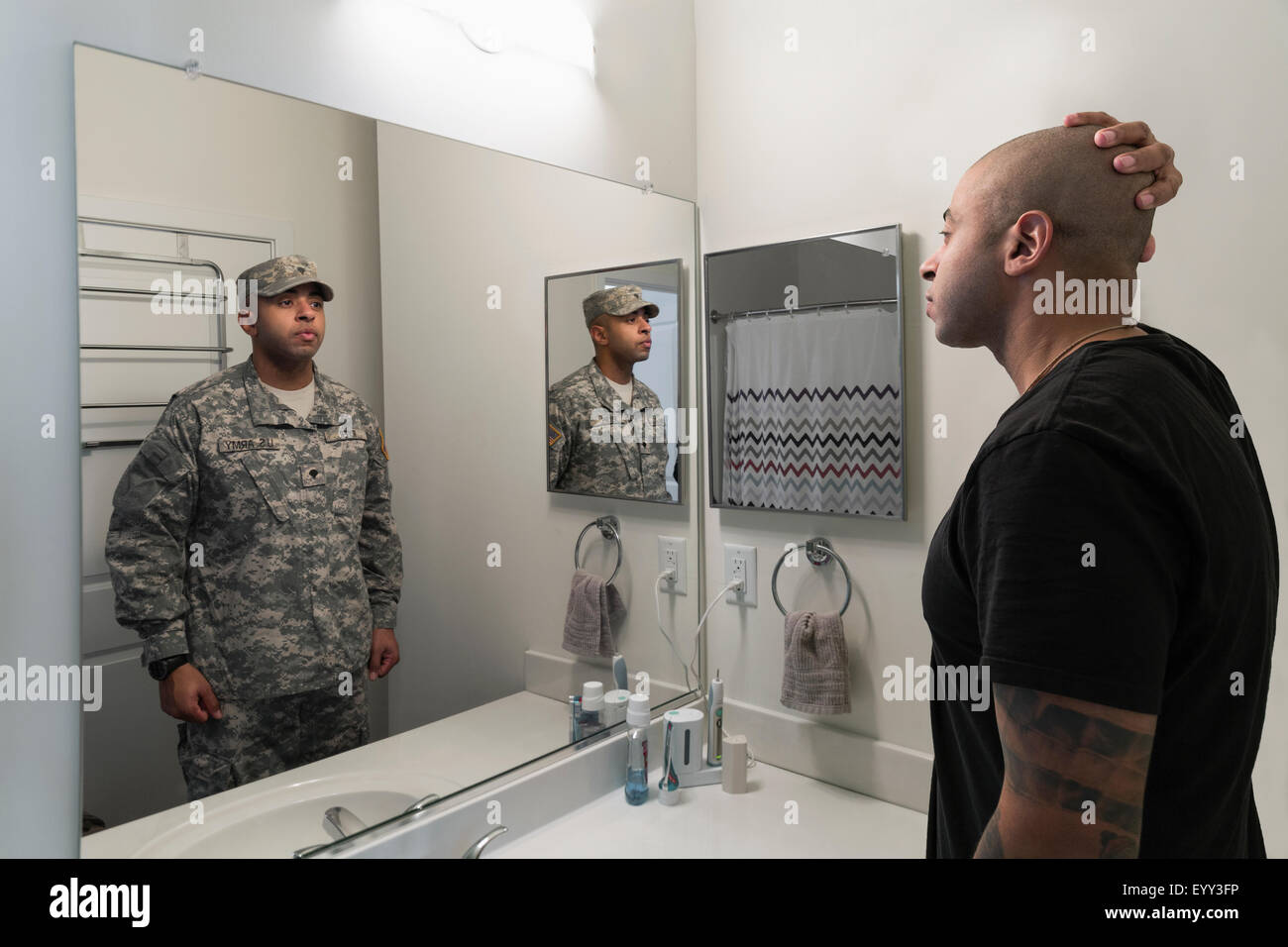 Mixed race man seeing soldier in mirror Stock Photo