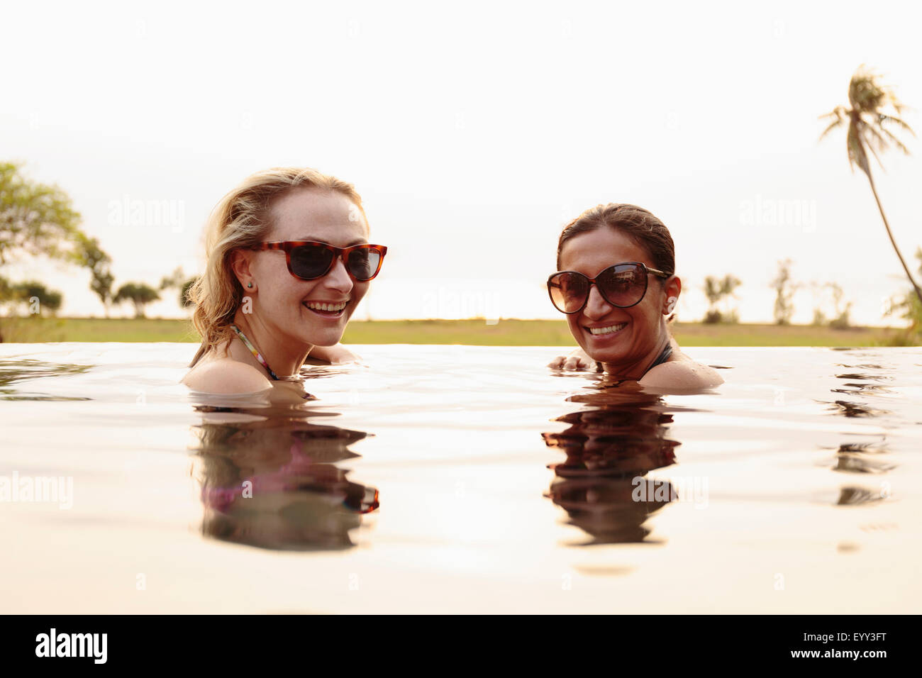 Smiling women swimming in infinity pool Stock Photo