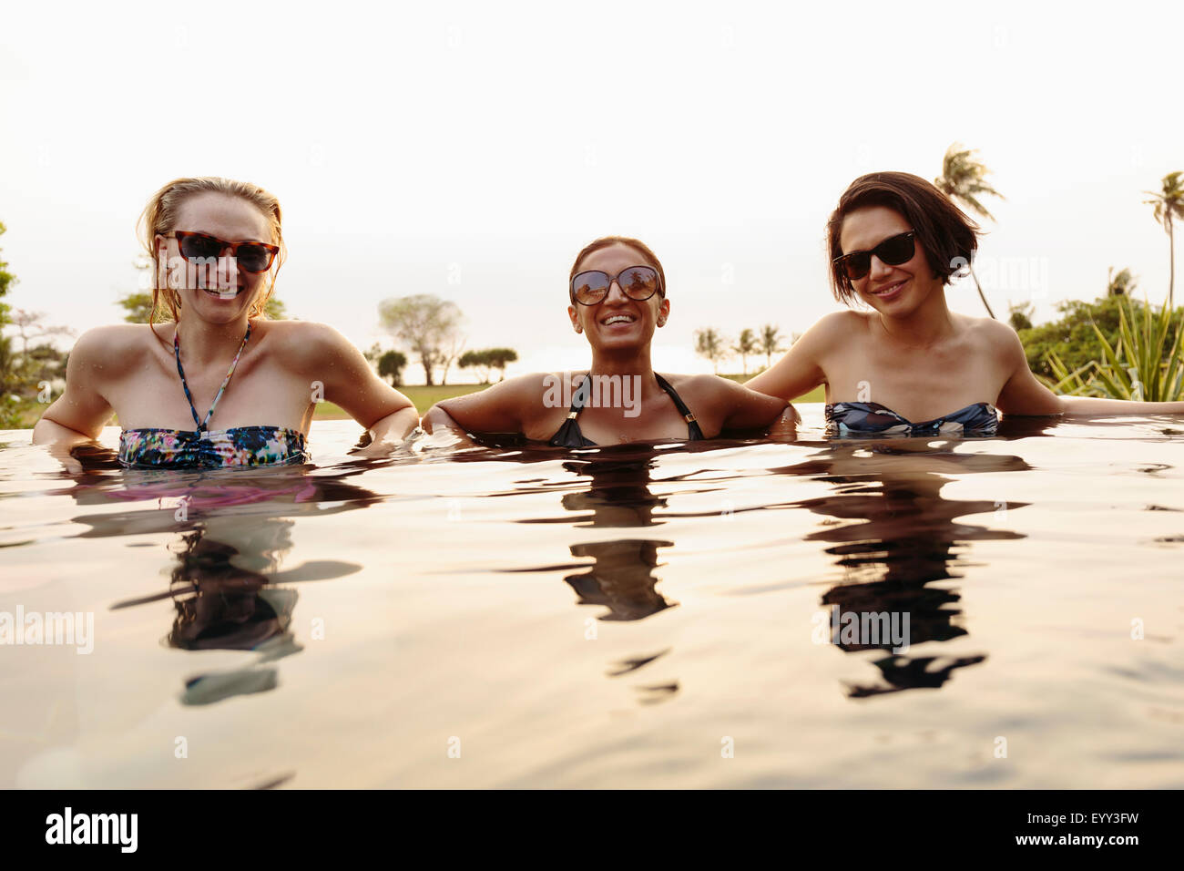 Smiling women relaxing in infinity pool Stock Photo