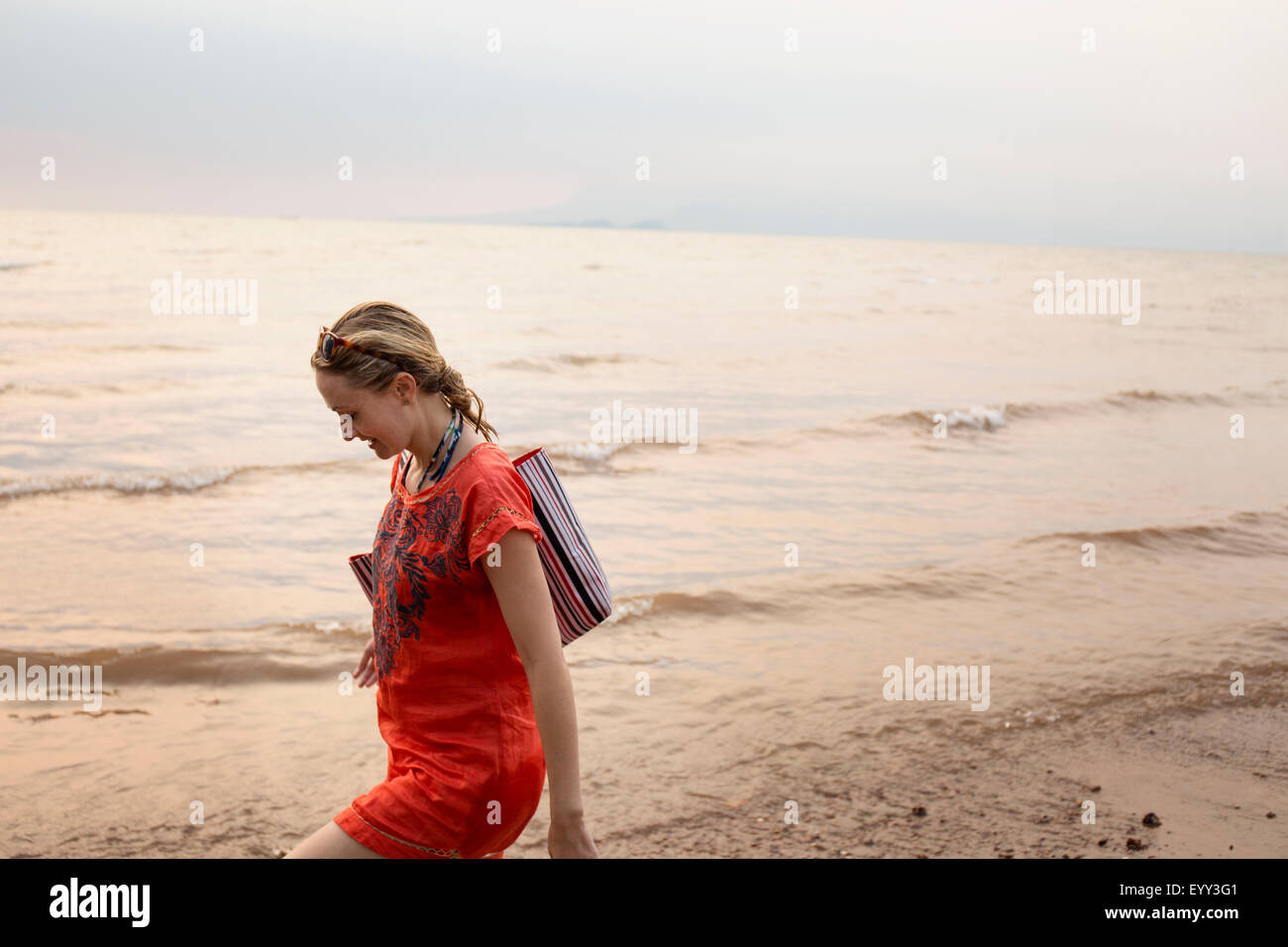 Caucasian woman walking on beach Stock Photo