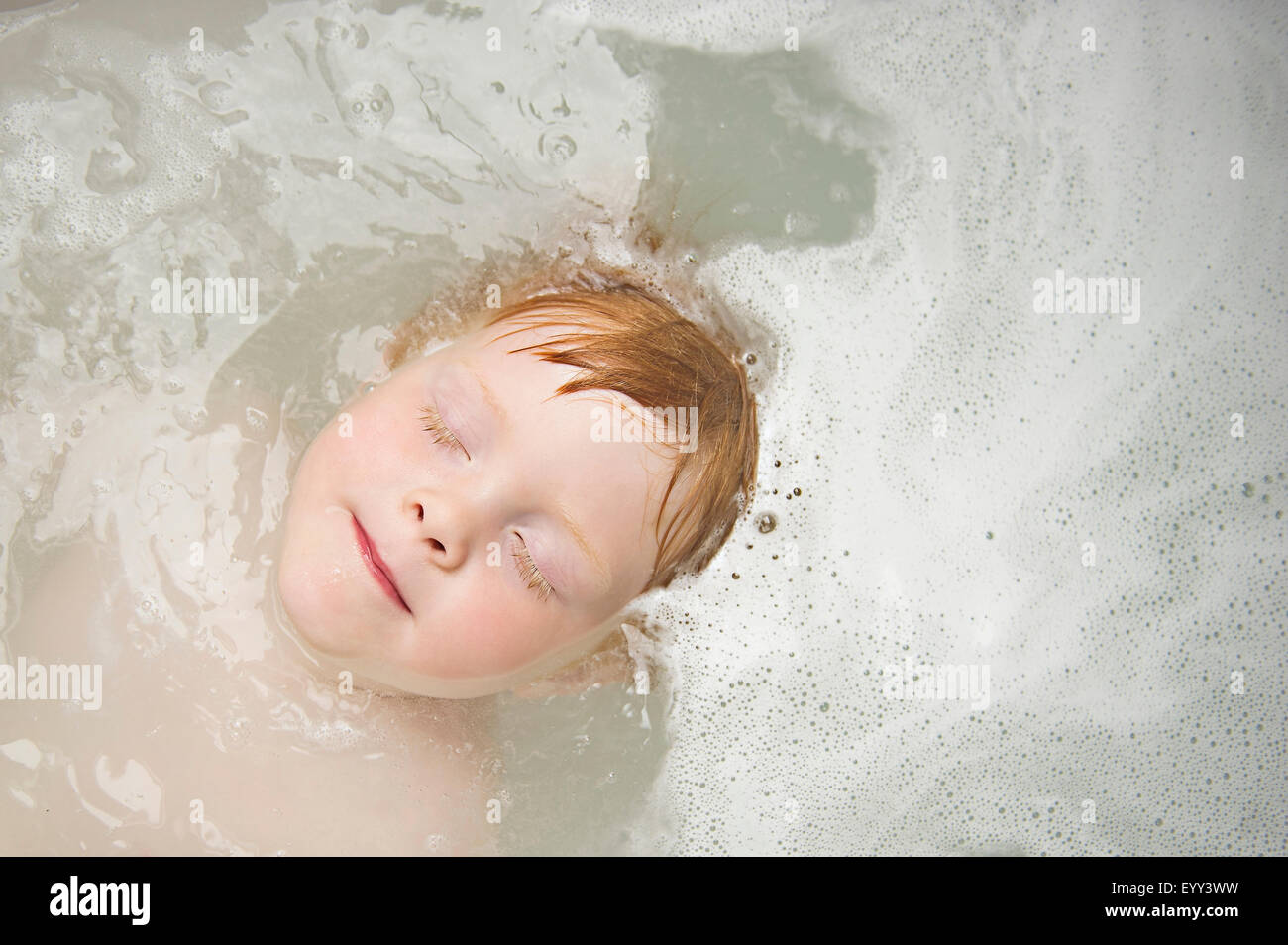 Caucasian boy with eyes closed in bubble bath Stock Photo