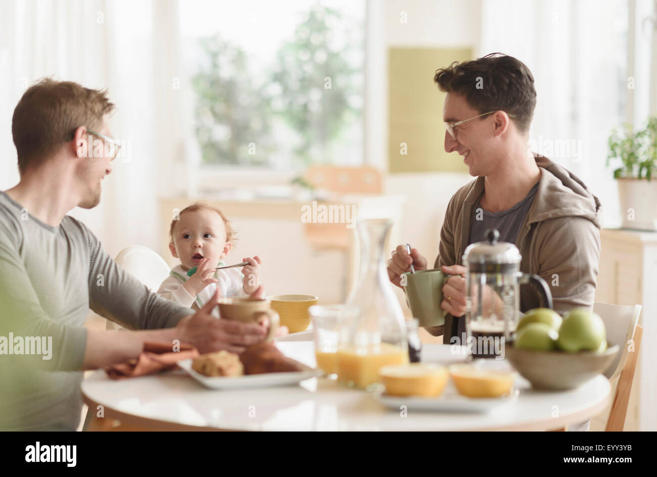 Caucasian gay fathers and baby eating breakfast Stock Photo