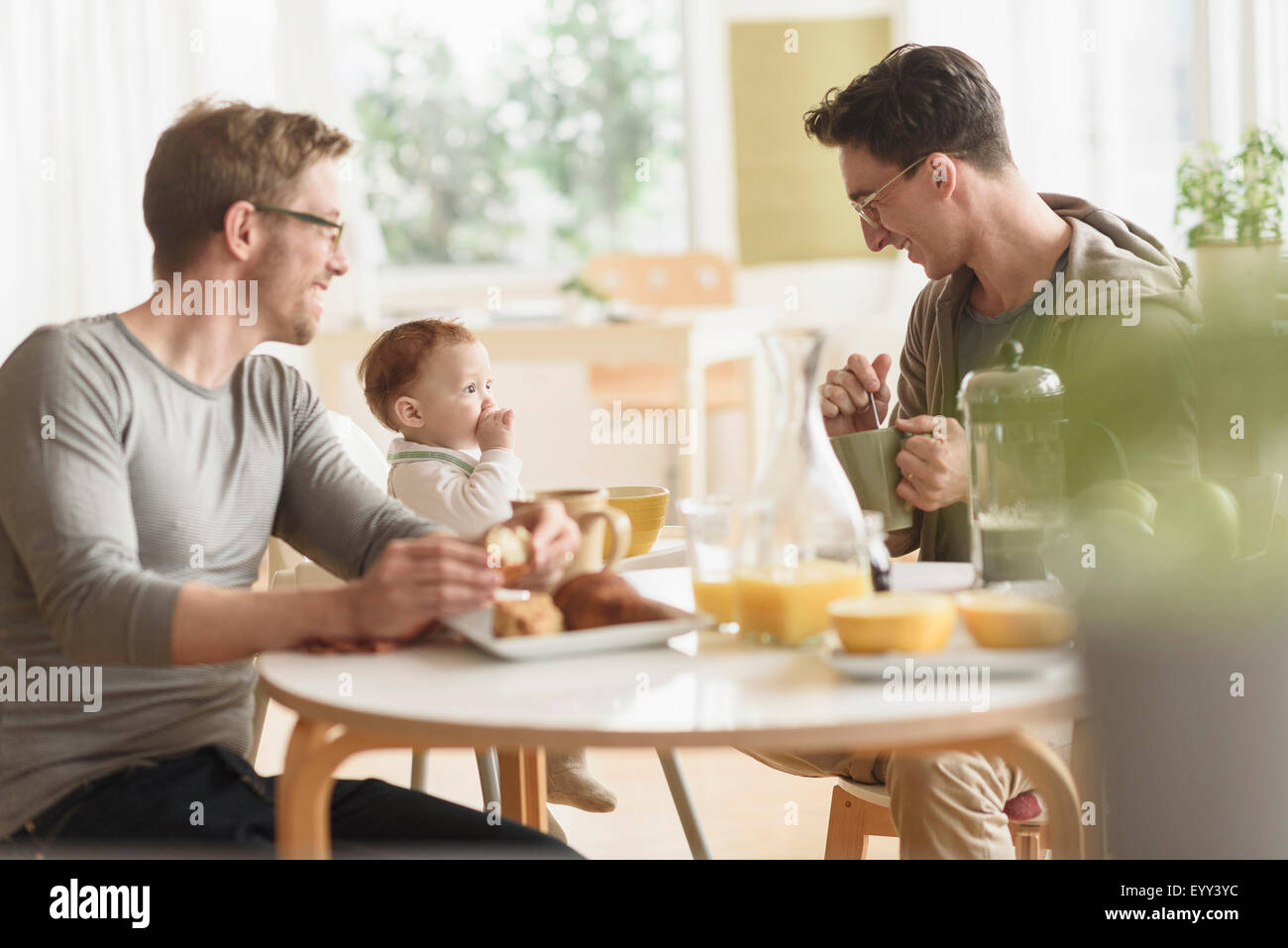 Caucasian gay fathers and baby eating breakfast Stock Photo