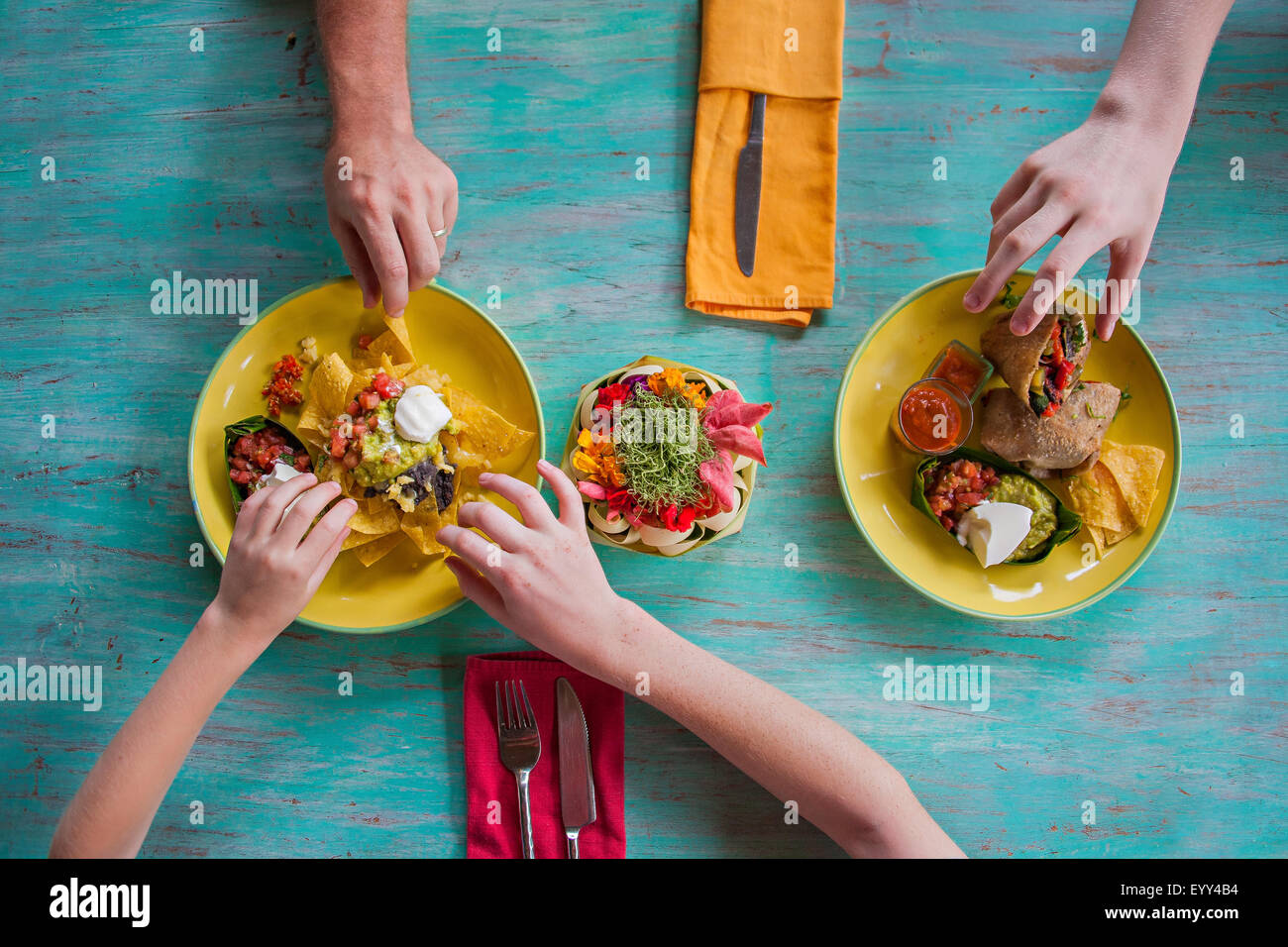 High angle view of hands reaching for food on plates Stock Photo