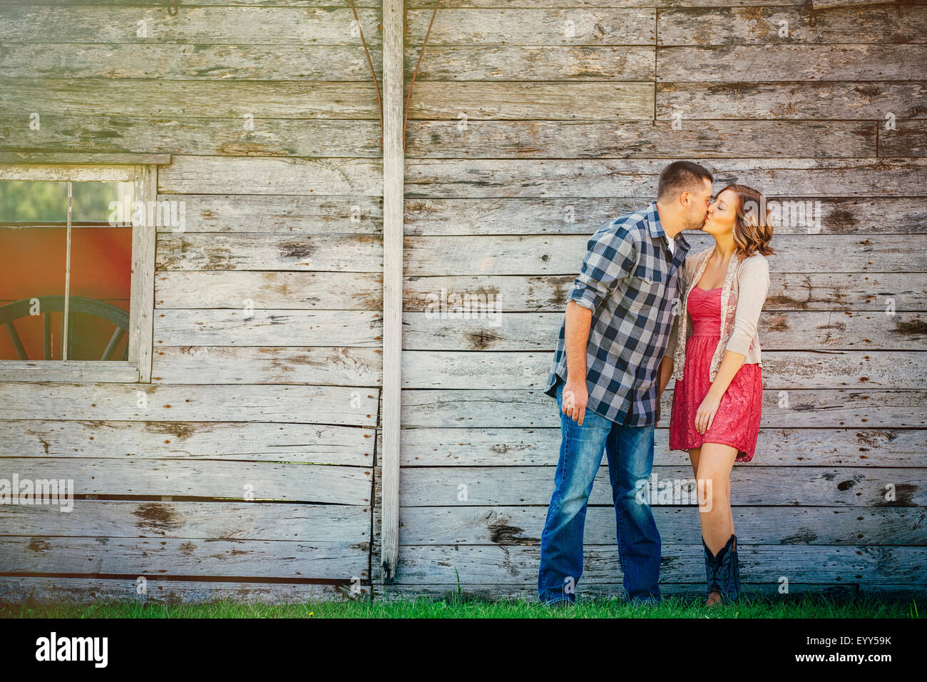 Caucasian couple kissing near wooden building Stock Photo