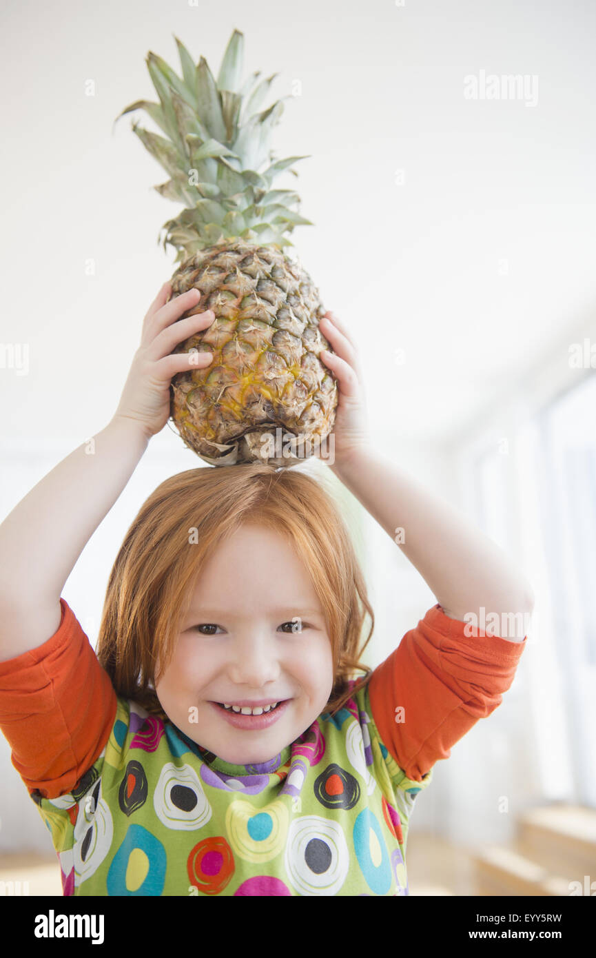 Caucasian girl balancing pineapple on head Stock Photo