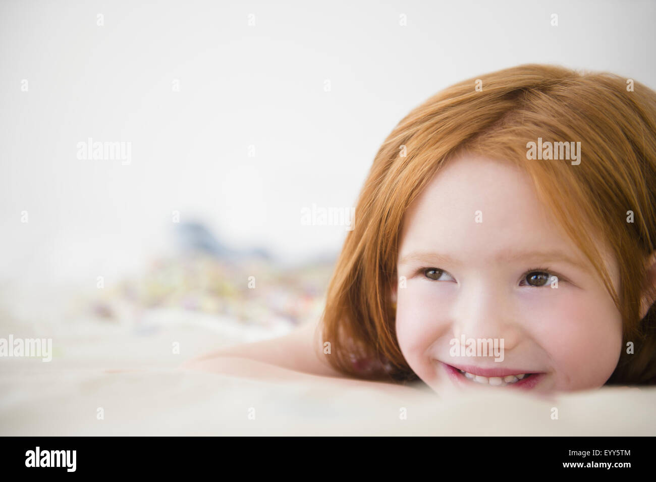 Smiling Caucasian girl laying on bed Stock Photo