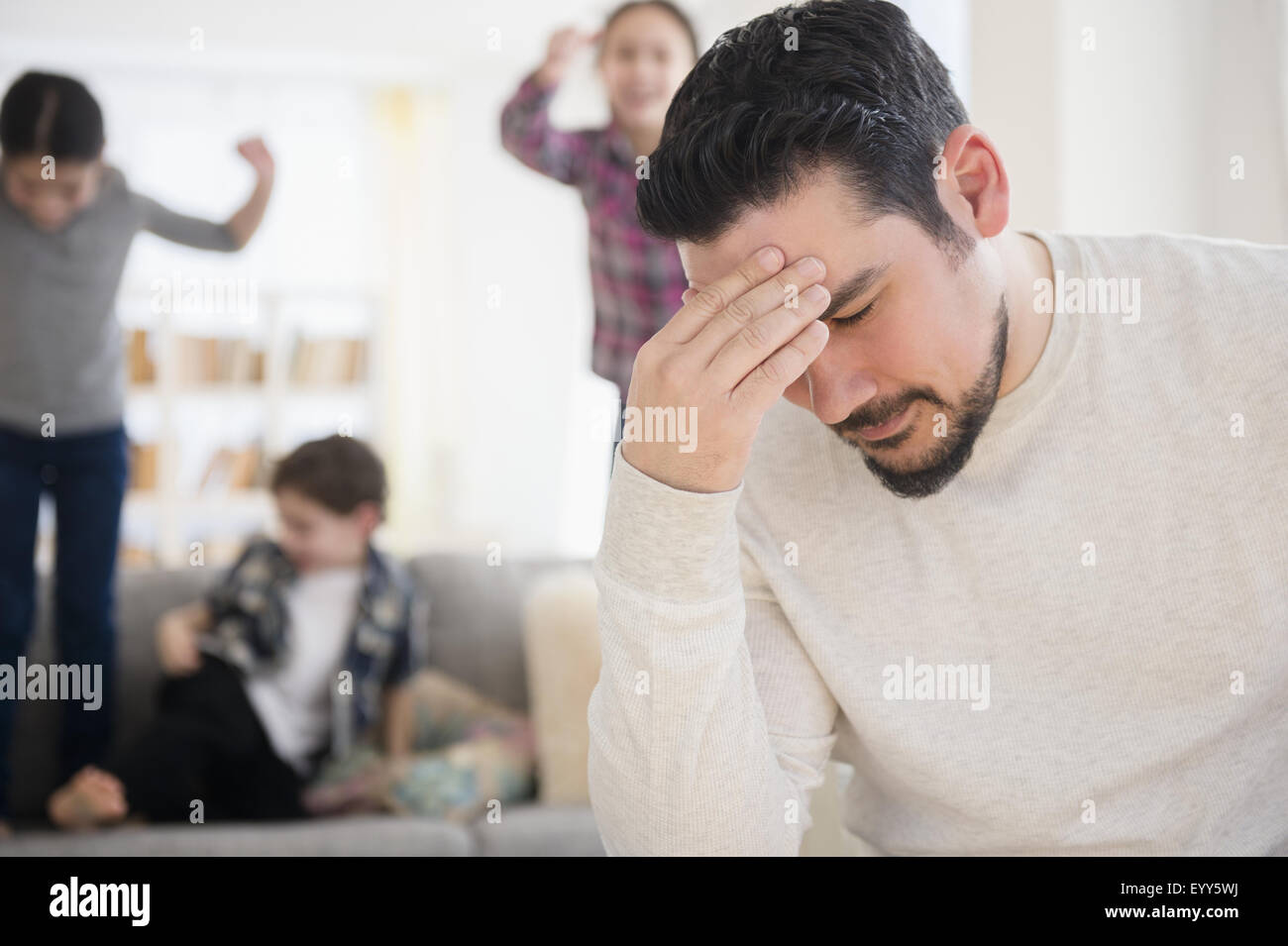 Stressed Caucasian father with shouting children in living room Stock Photo