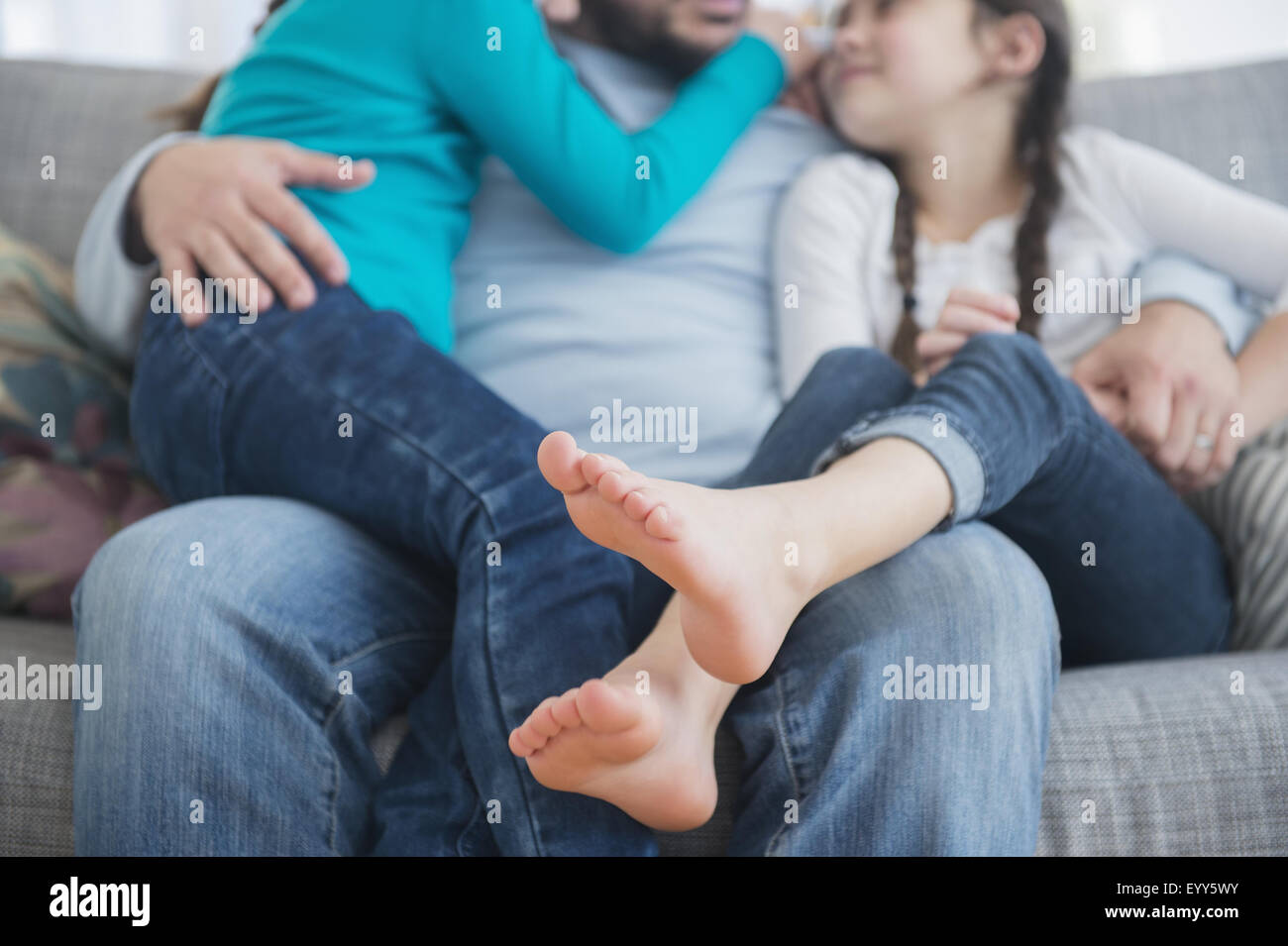 Caucasian father and daughters hugging on sofa Stock Photo