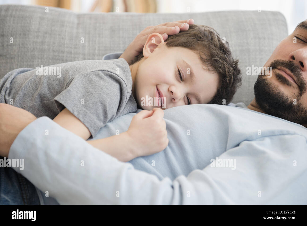 Caucasian father and son napping on sofa Stock Photo