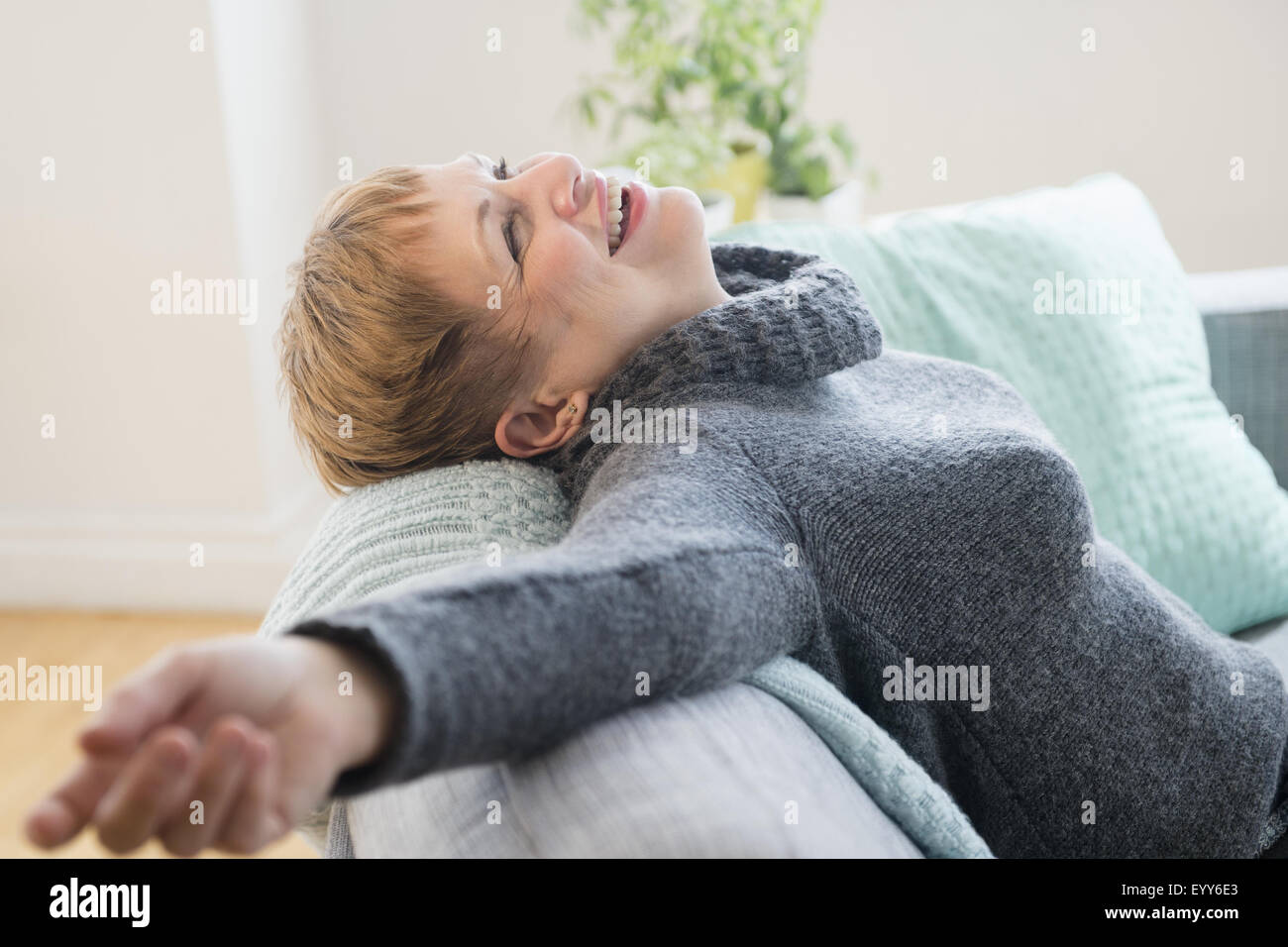 Laughing Caucasian woman laying on sofa Stock Photo